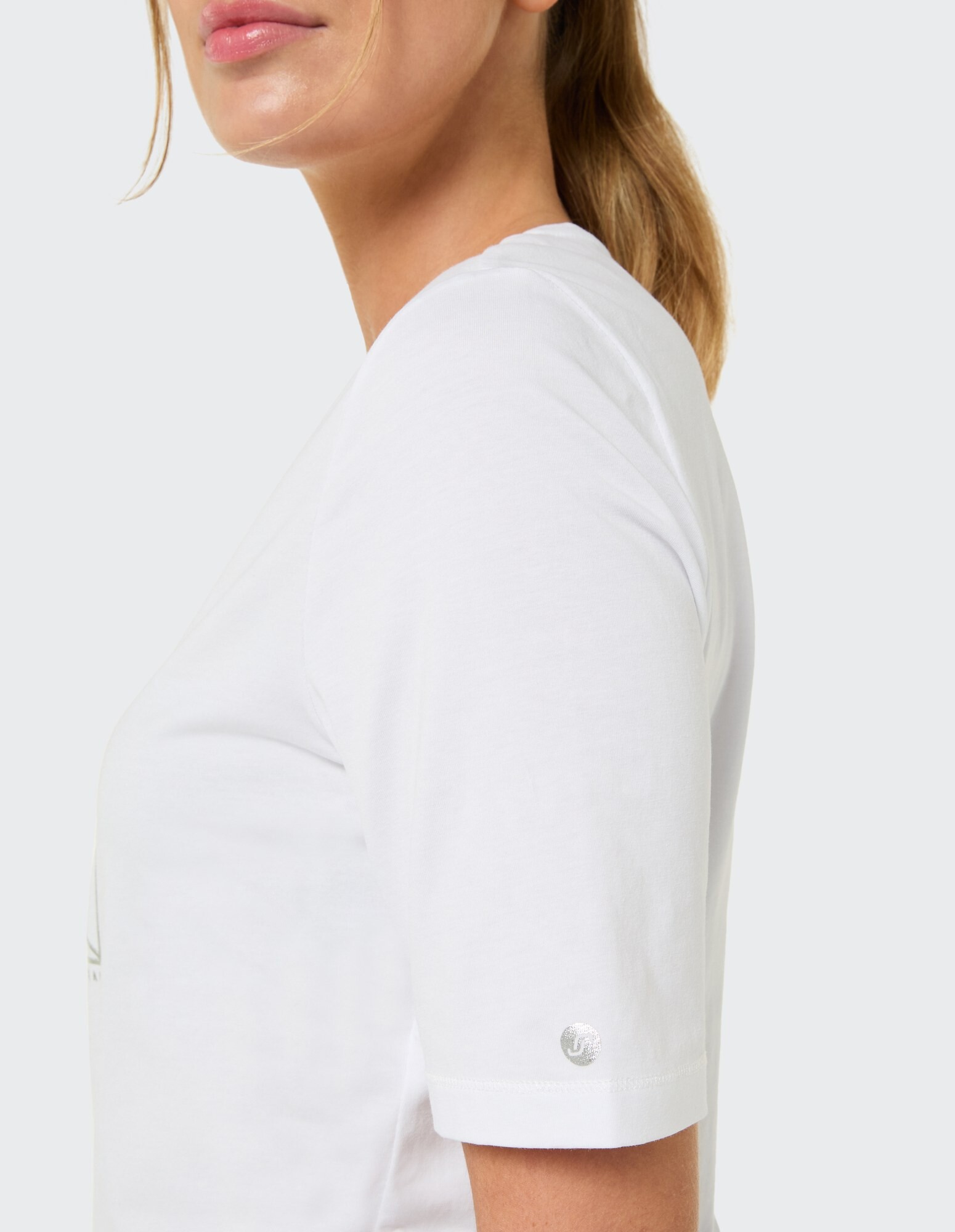 Nahaufnahme einer Frau, die ein weißes Freizeit-T-Shirt mit kurzen Ärmeln trägt.