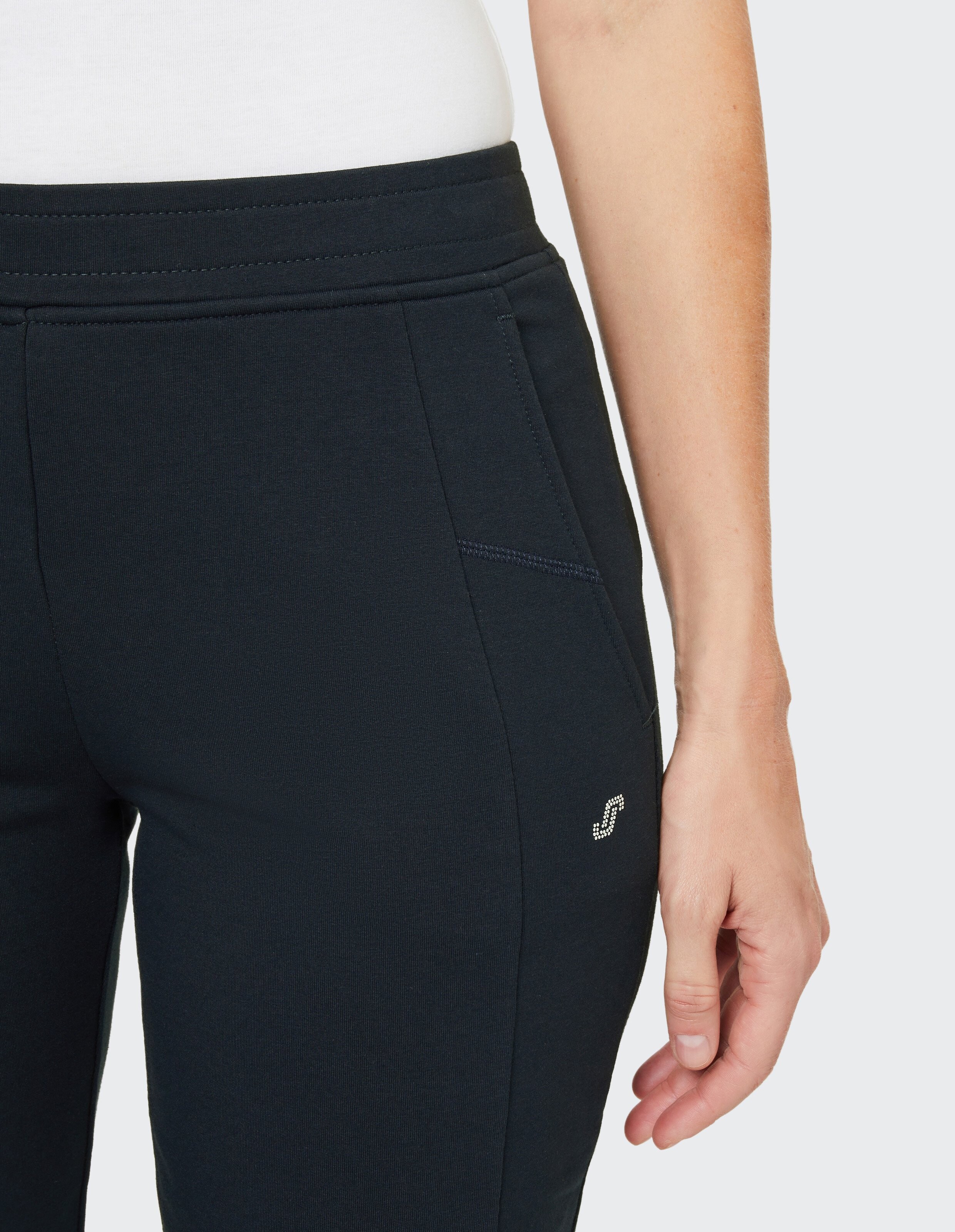 Eine Person trägt dunkelblaue Jogginghose mit weißem Shirt