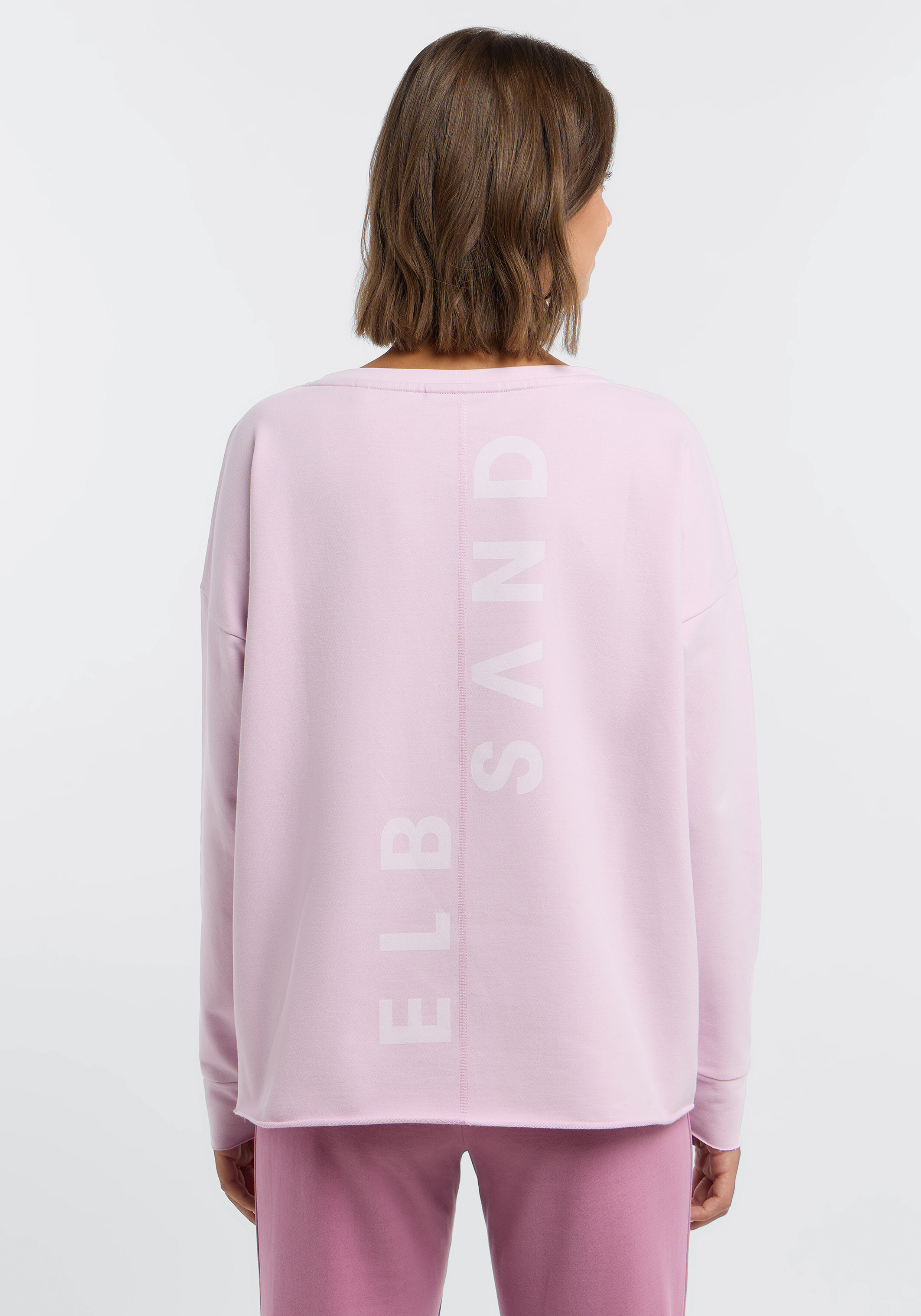 Frau trägt ein hellrosa ELBSAND Casual-Lounge-Sweatshirt von hinten.