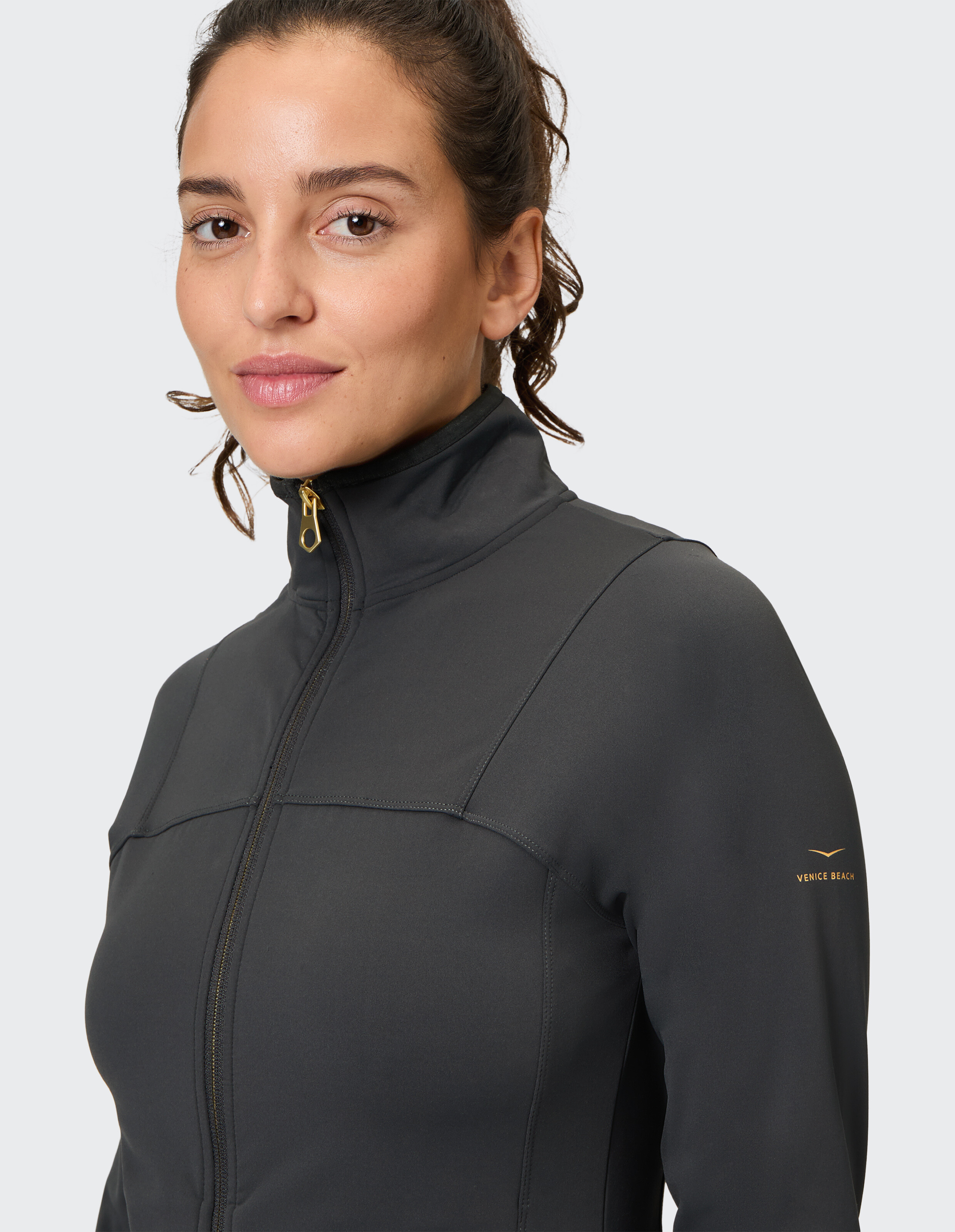 Nahaufnahme einer Frau in einer schwarzen Jacke mit Reißverschluss, die ein elegantes, sportliches Design zeigt.