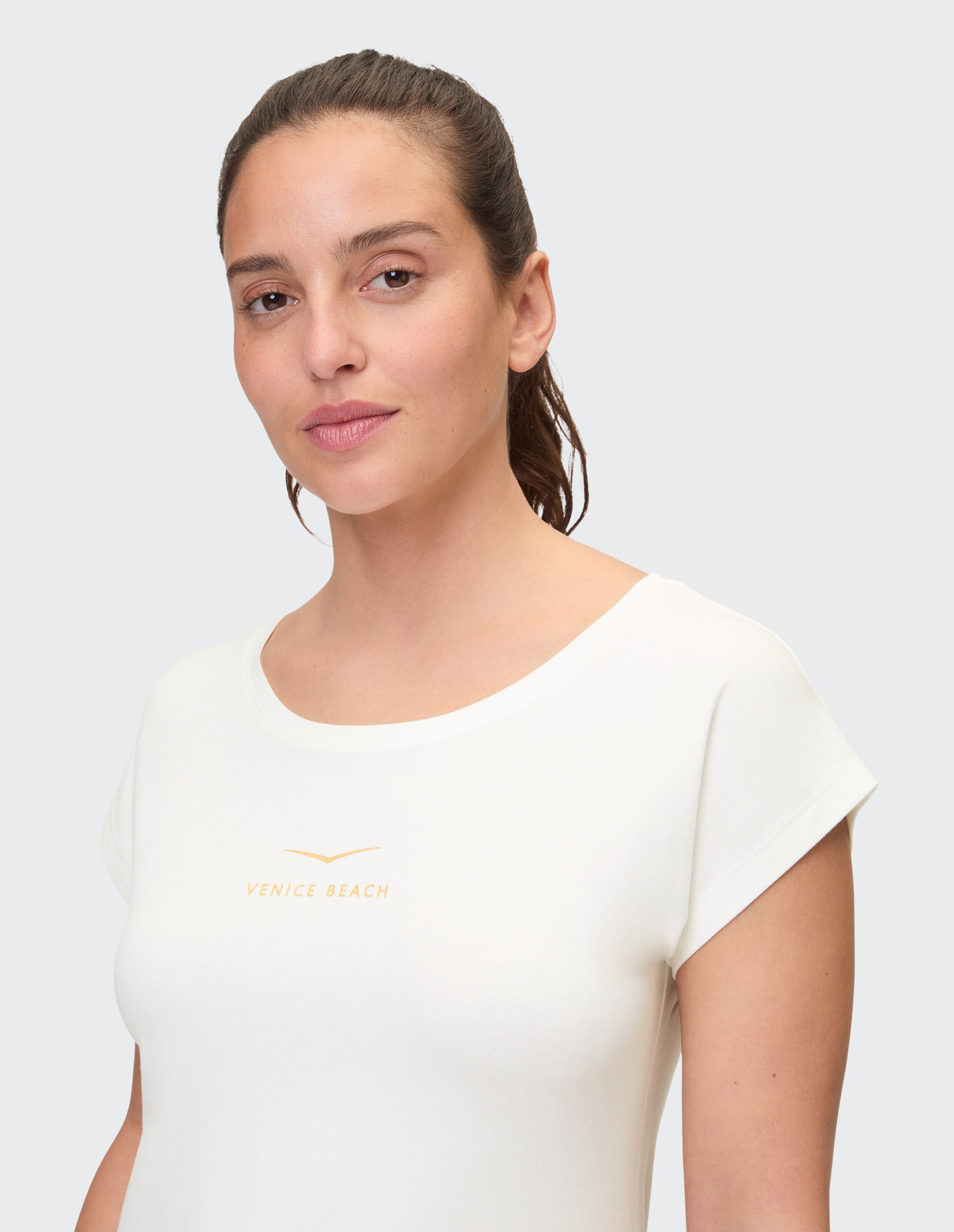 Frau trägt ein weißes, lässiges Venice Beach-T-Shirt für bequemen Alltagsstil.
