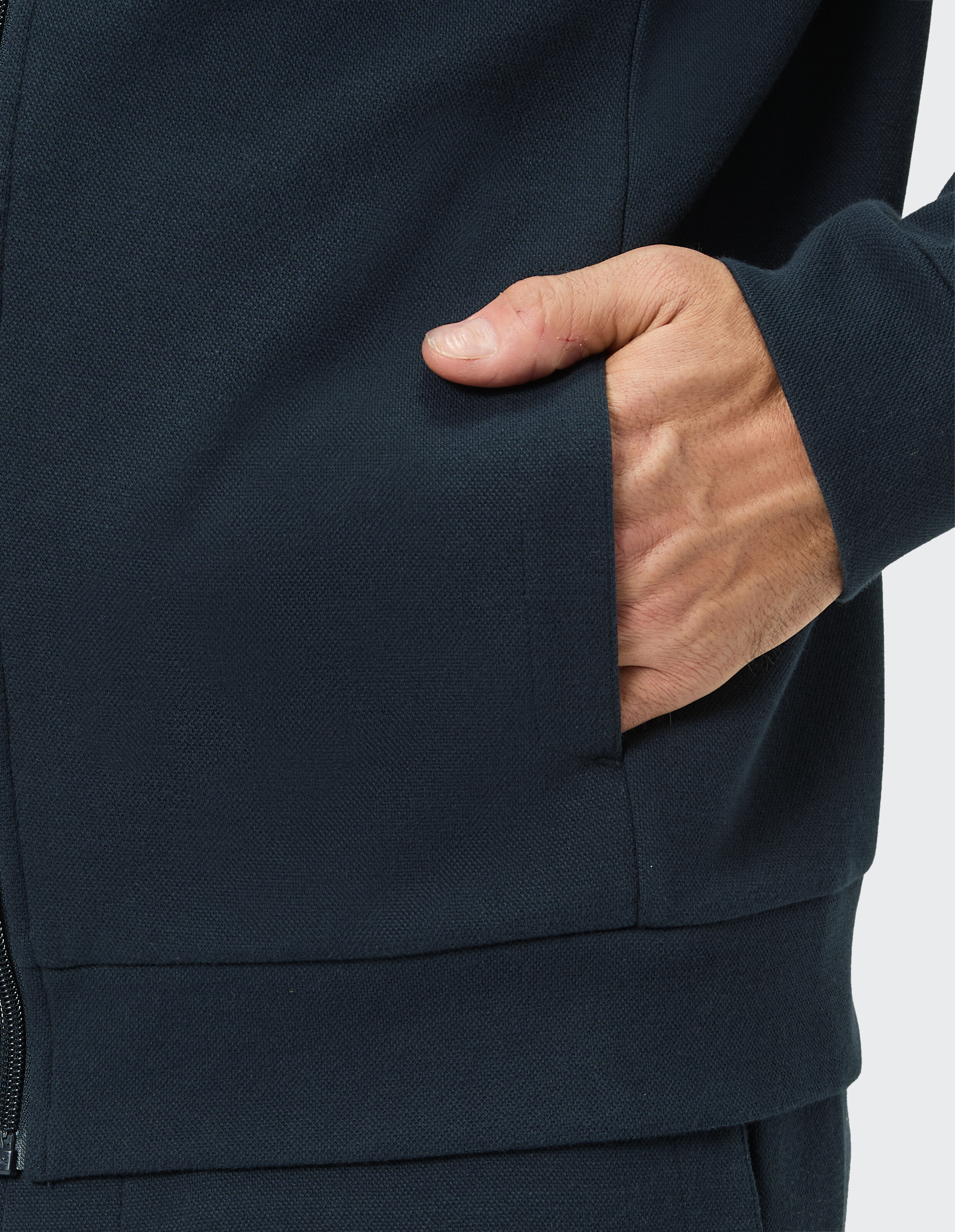 Nahaufnahme einer dunkelblauen Freizeitjacke mit einer Hand in der Tasche.