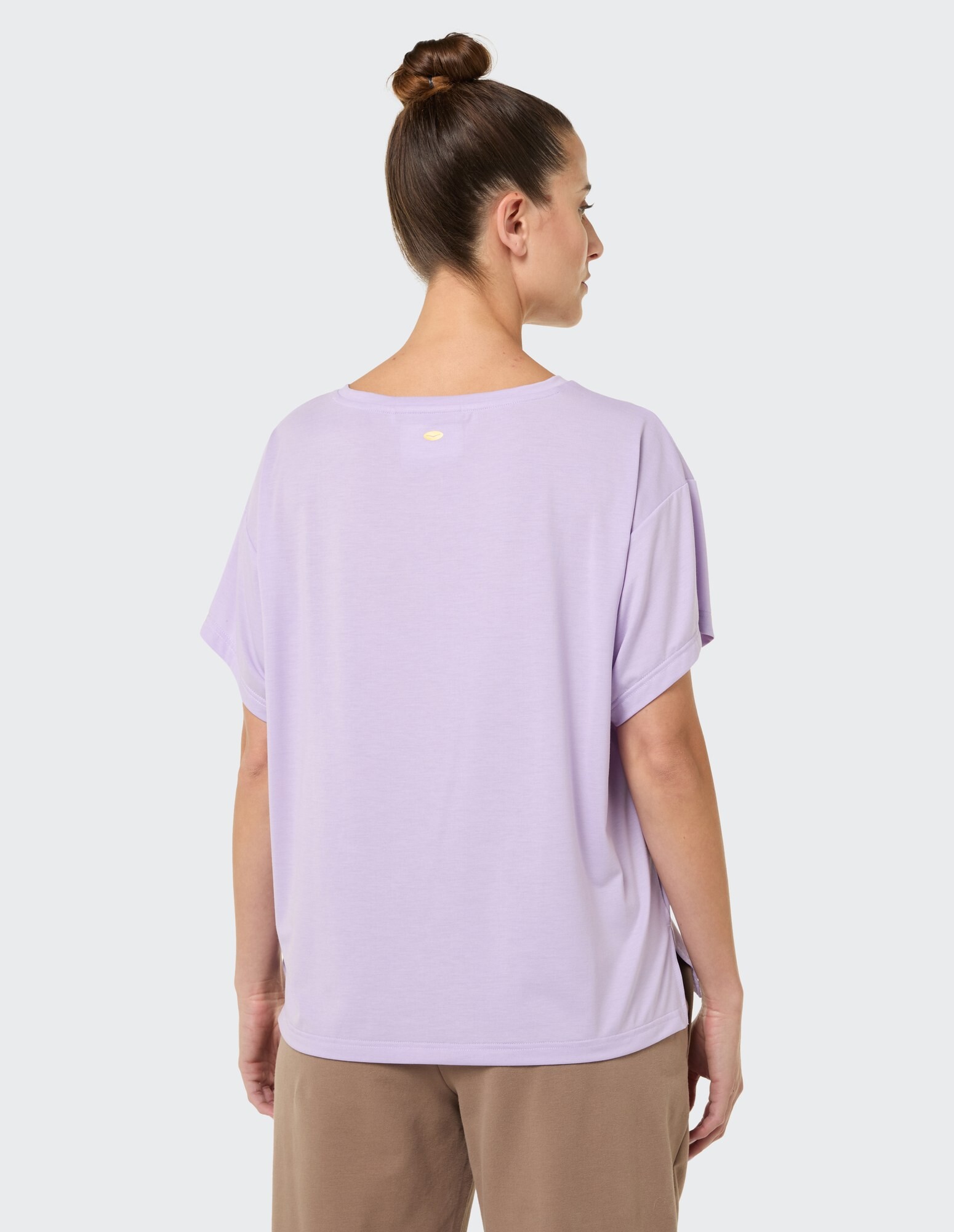 Rückansicht einer Frau, die ein locker sitzendes lavendelfarbenes T-Shirt für Freizeitkleidung trägt.