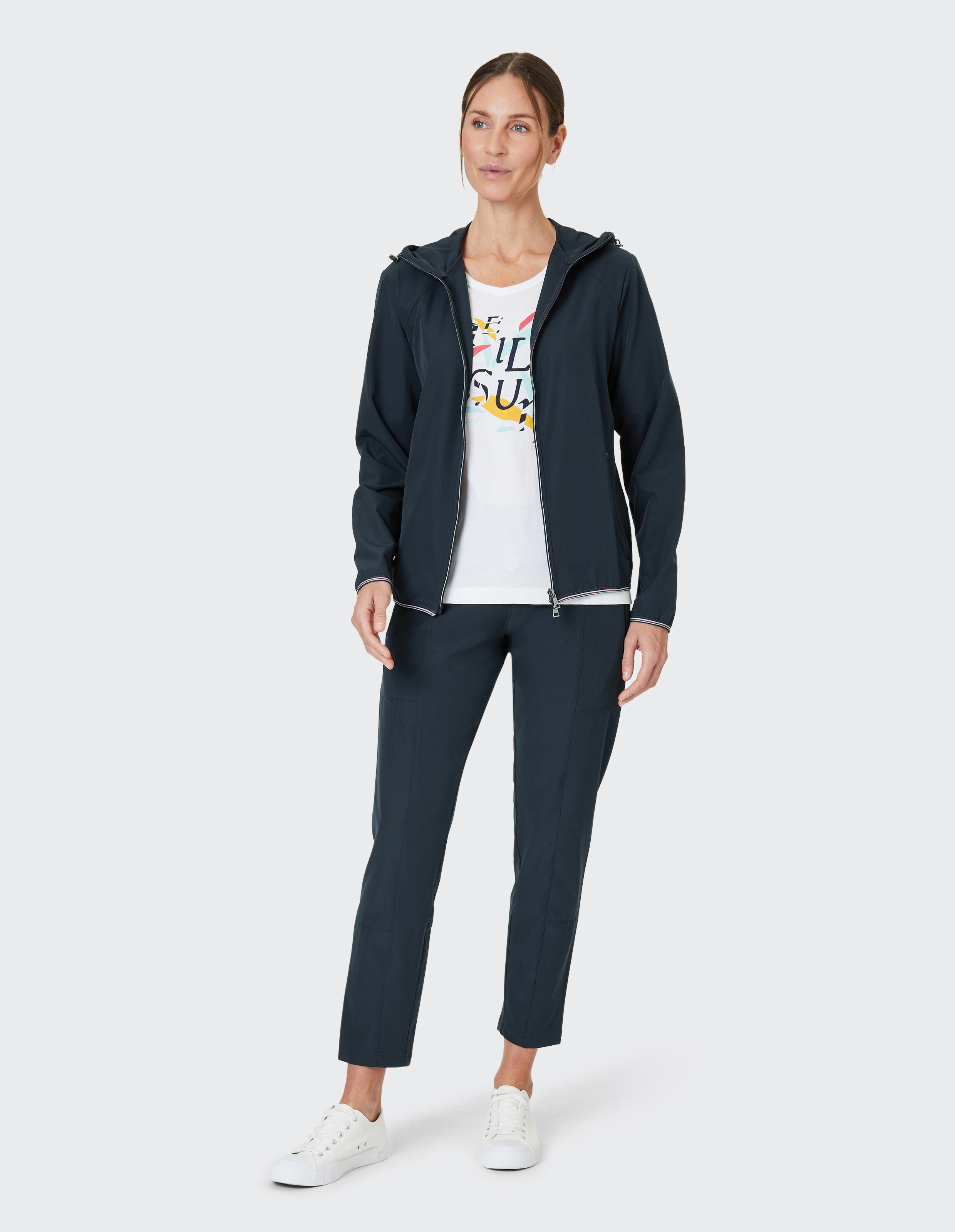 Frau in dunkelblauer Freizeitjacke und -hose mit farbenfrohem Grafik-T-Shirt, perfekt für entspannte Ausflüge.