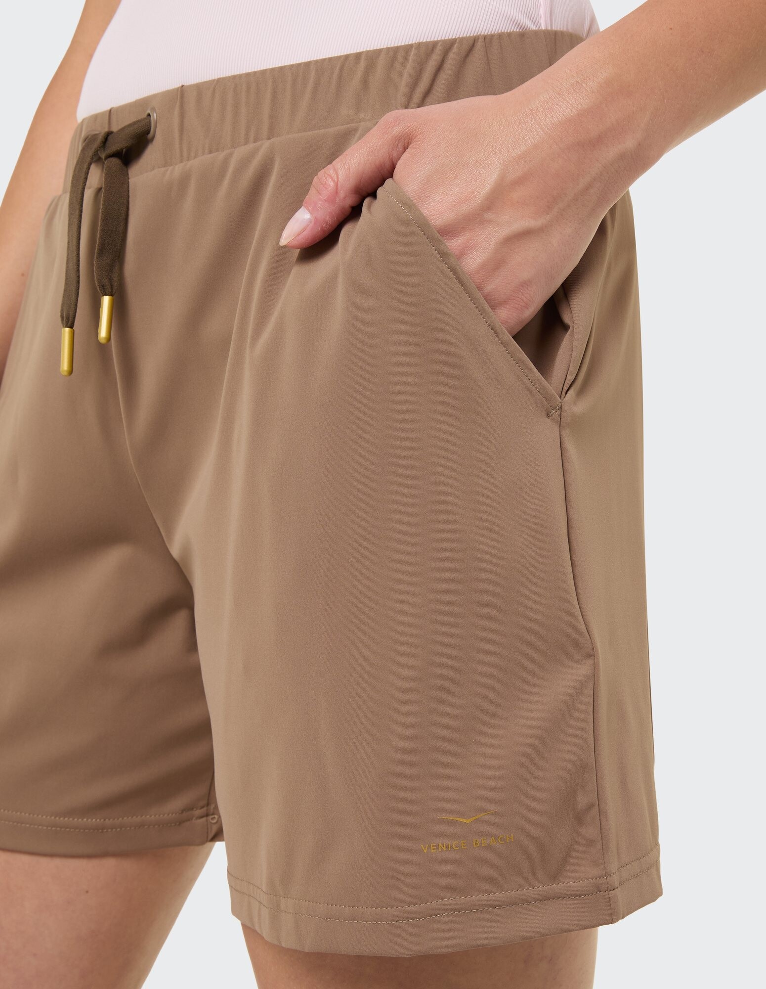 Nahaufnahme beigefarbener Freizeitshorts mit Taschen und Kordelzugdetail.