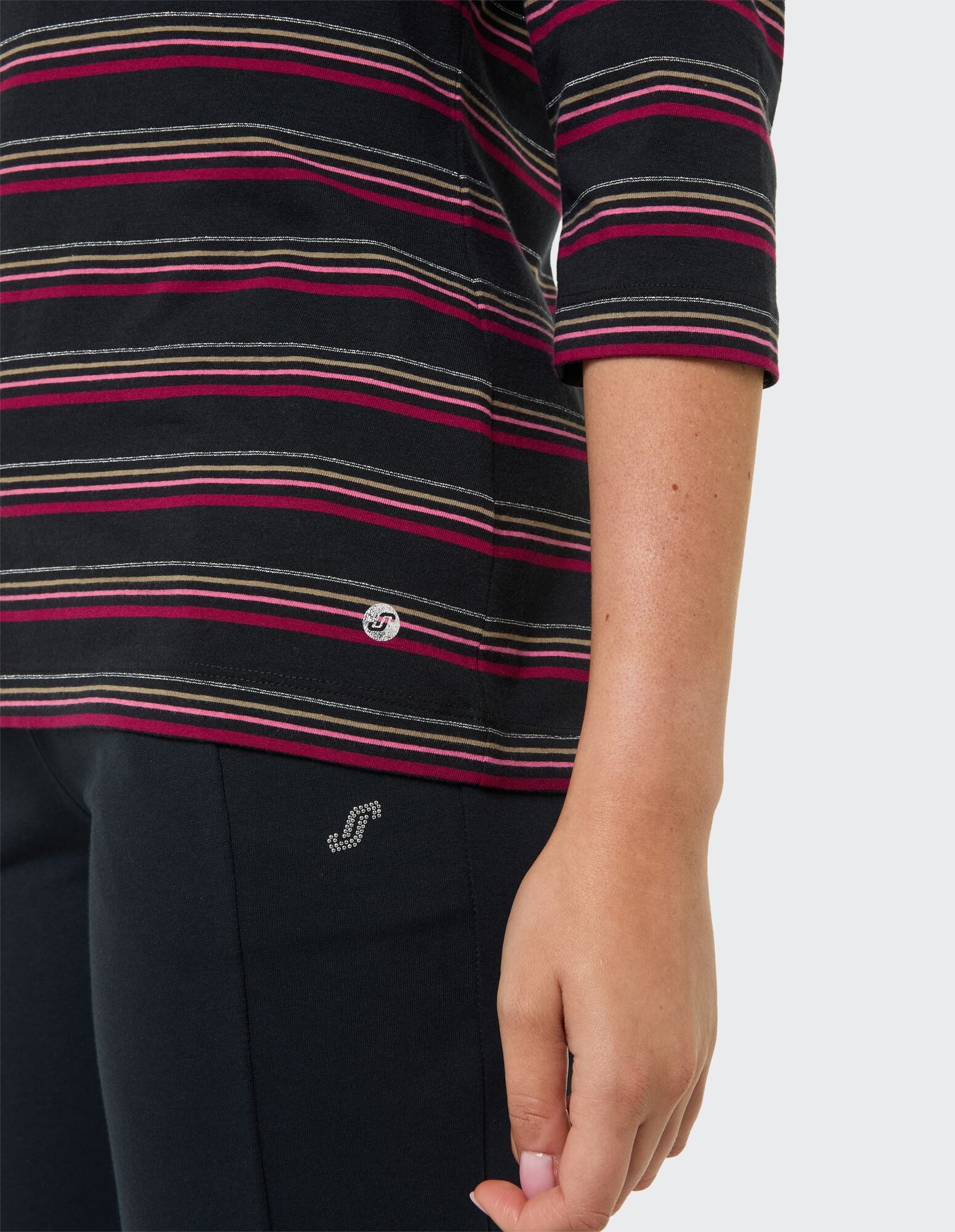 Nahaufnahme eines gestreiften Freizeitoberteils mit Dreiviertelärmeln und einer schwarzen Hose.