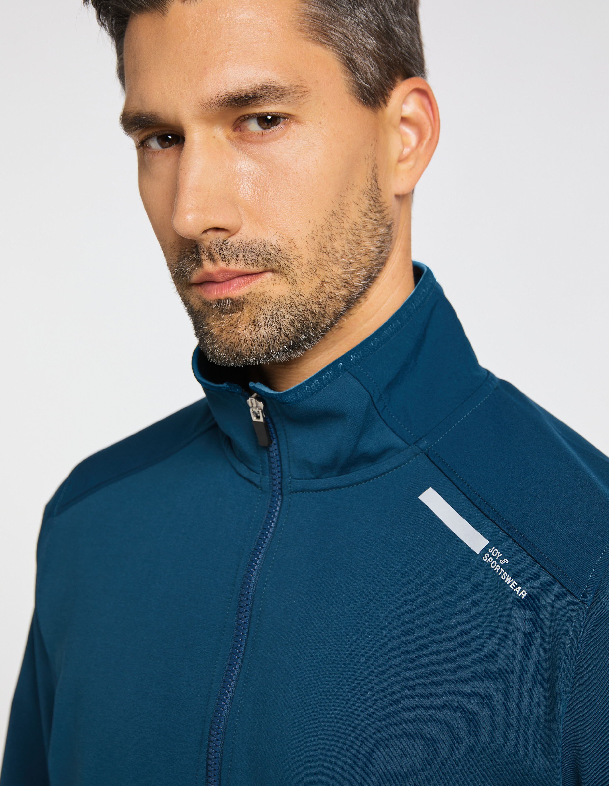 Blaue Jacke mit durchgehendem Reißverschluss, hohem Kragen und zwei seitlichen Taschen, ideal für sportliche Aktivitäten.
