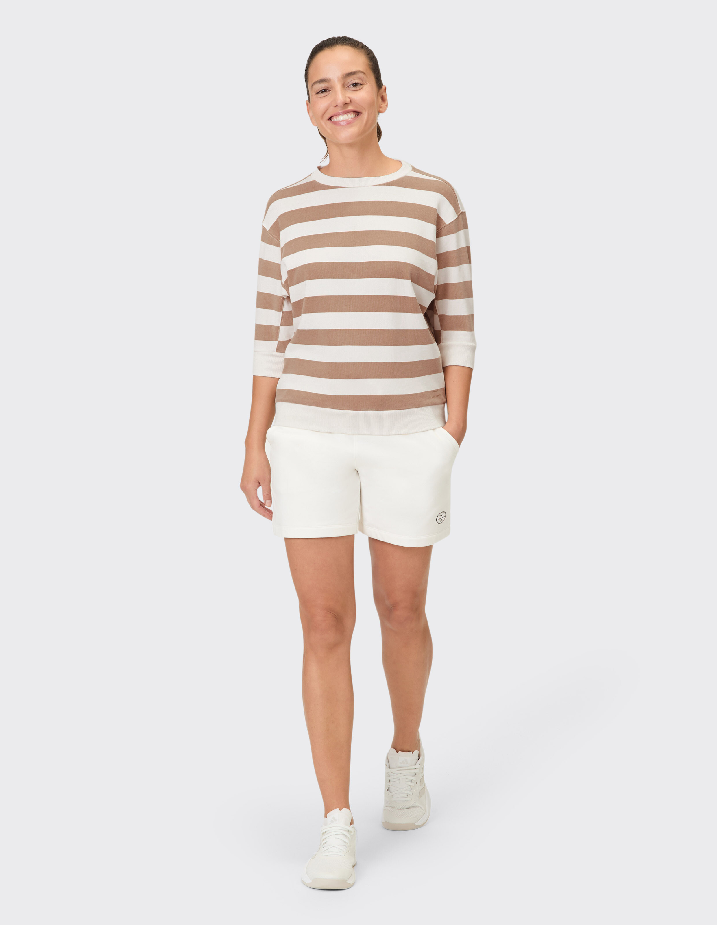 Frau trägt ein gemütliches gestreiftes Venice Beach Sweatshirt Janette mit weißen Shorts.