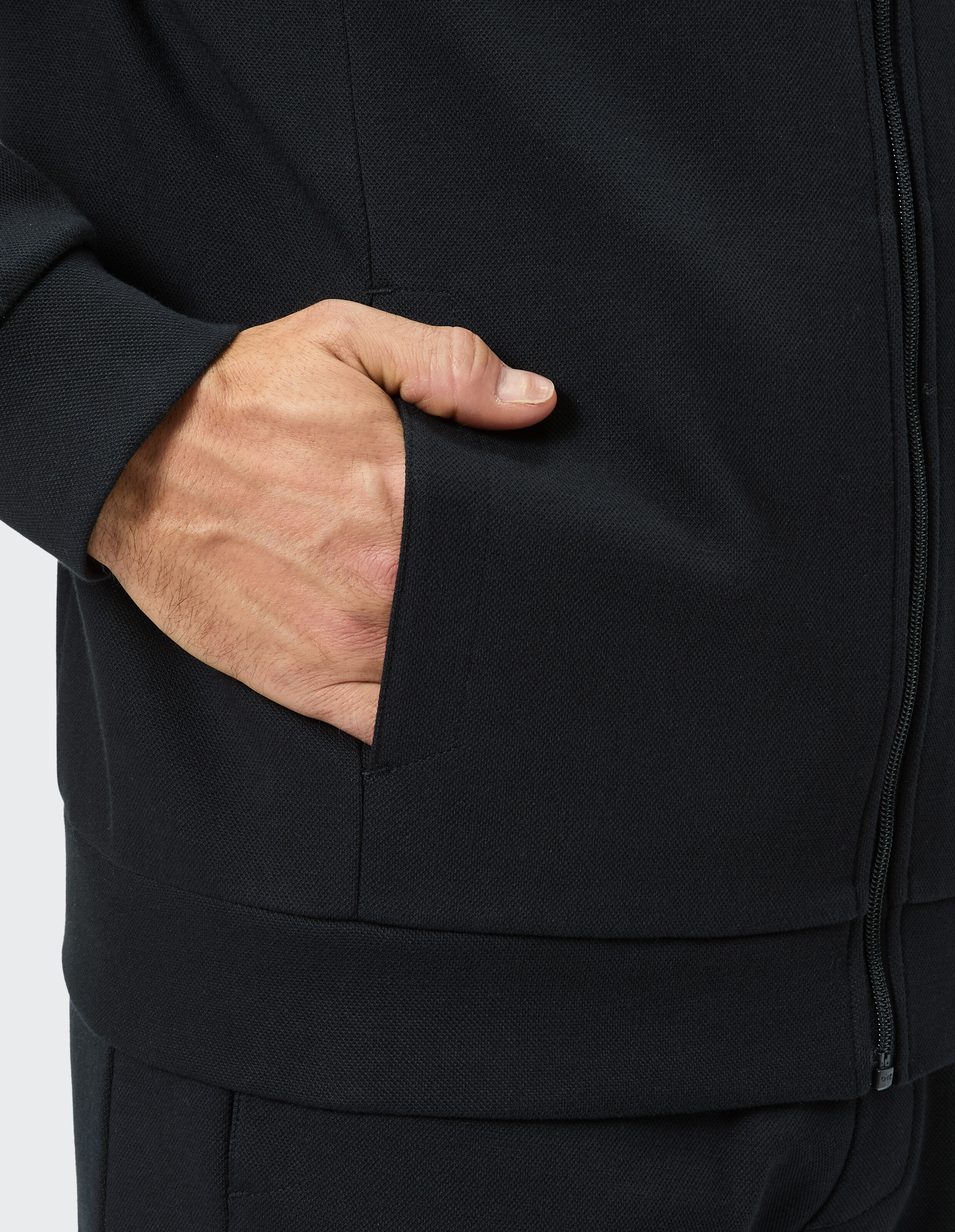 Nahaufnahme der Hand eines Mannes in der Tasche einer schwarzen Jacke mit Reißverschluss.