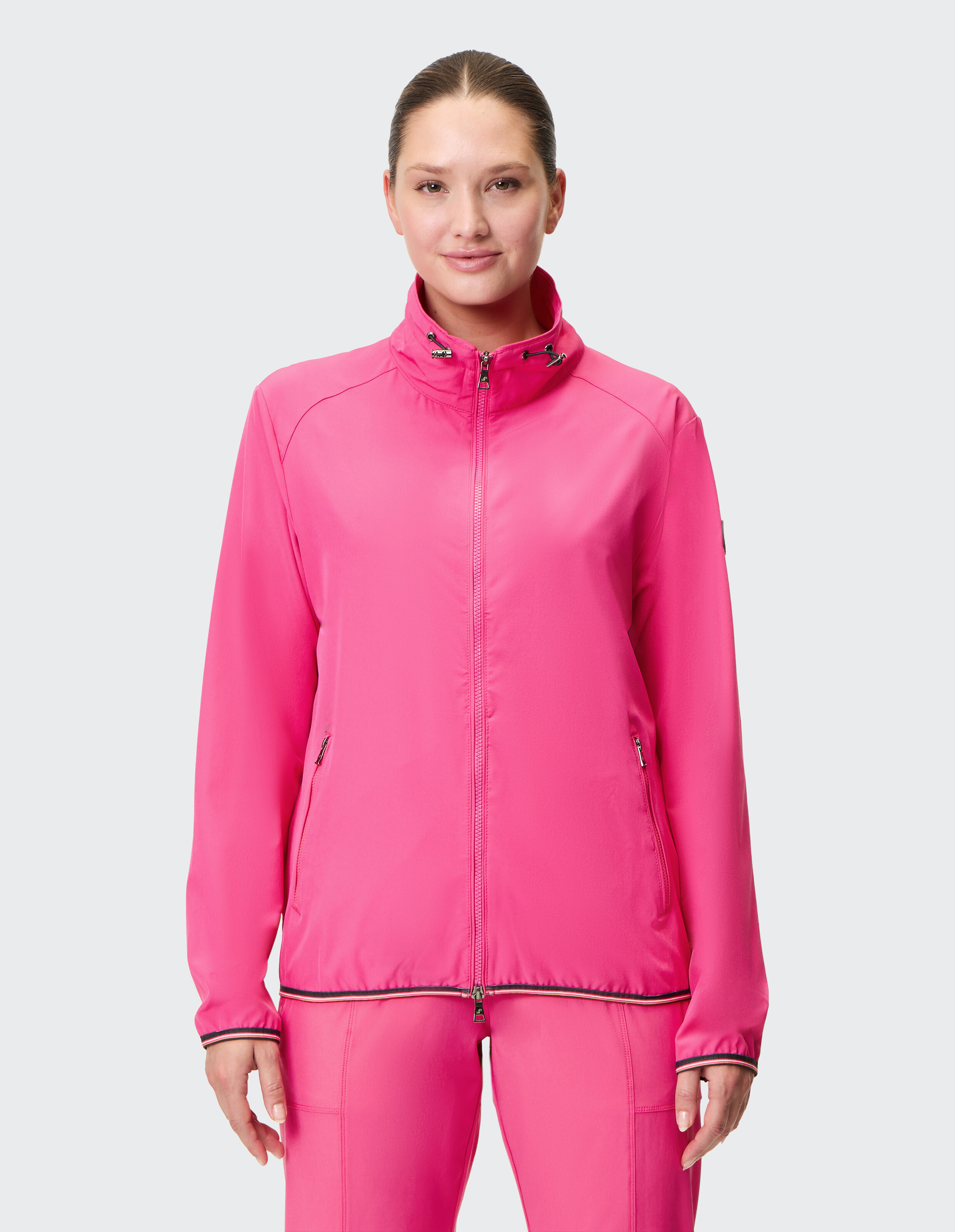 Frau trägt eine leuchtend rosa Jacke mit Reißverschluss, perfekt für Freizeitausflüge.