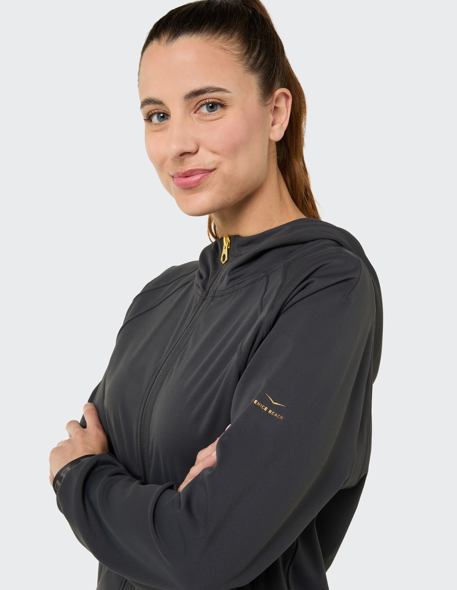 Frau in einem stilvollen dunkelgrauen Kapuzenpullover mit Reißverschluss und goldenen Akzenten, perfekt für Freizeitkleidung.