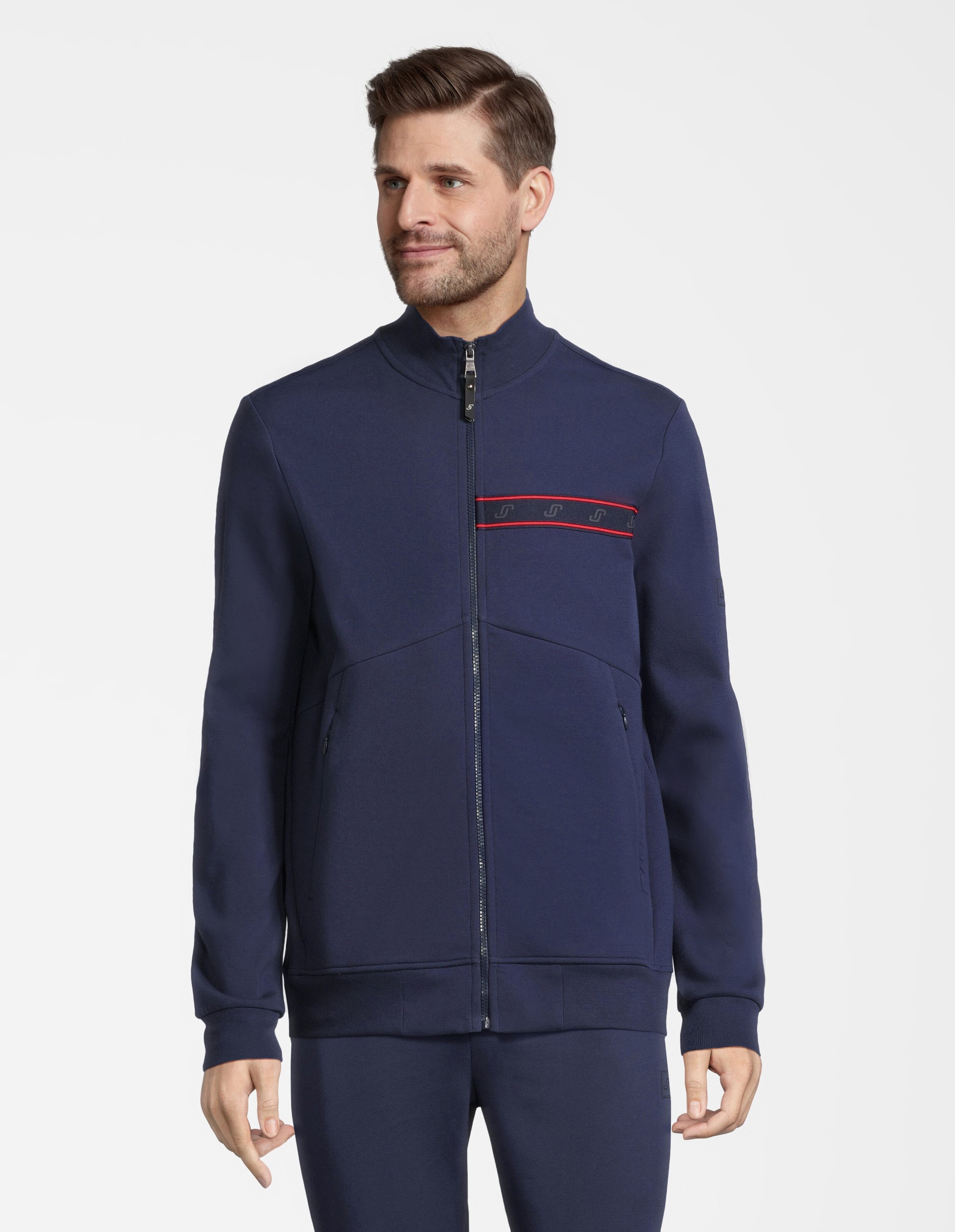 Dunkelblaue Jacke mit Reißverschluss, Stehkragen und einem dezenten roten Streifen über der Brust mit Logos verziert.