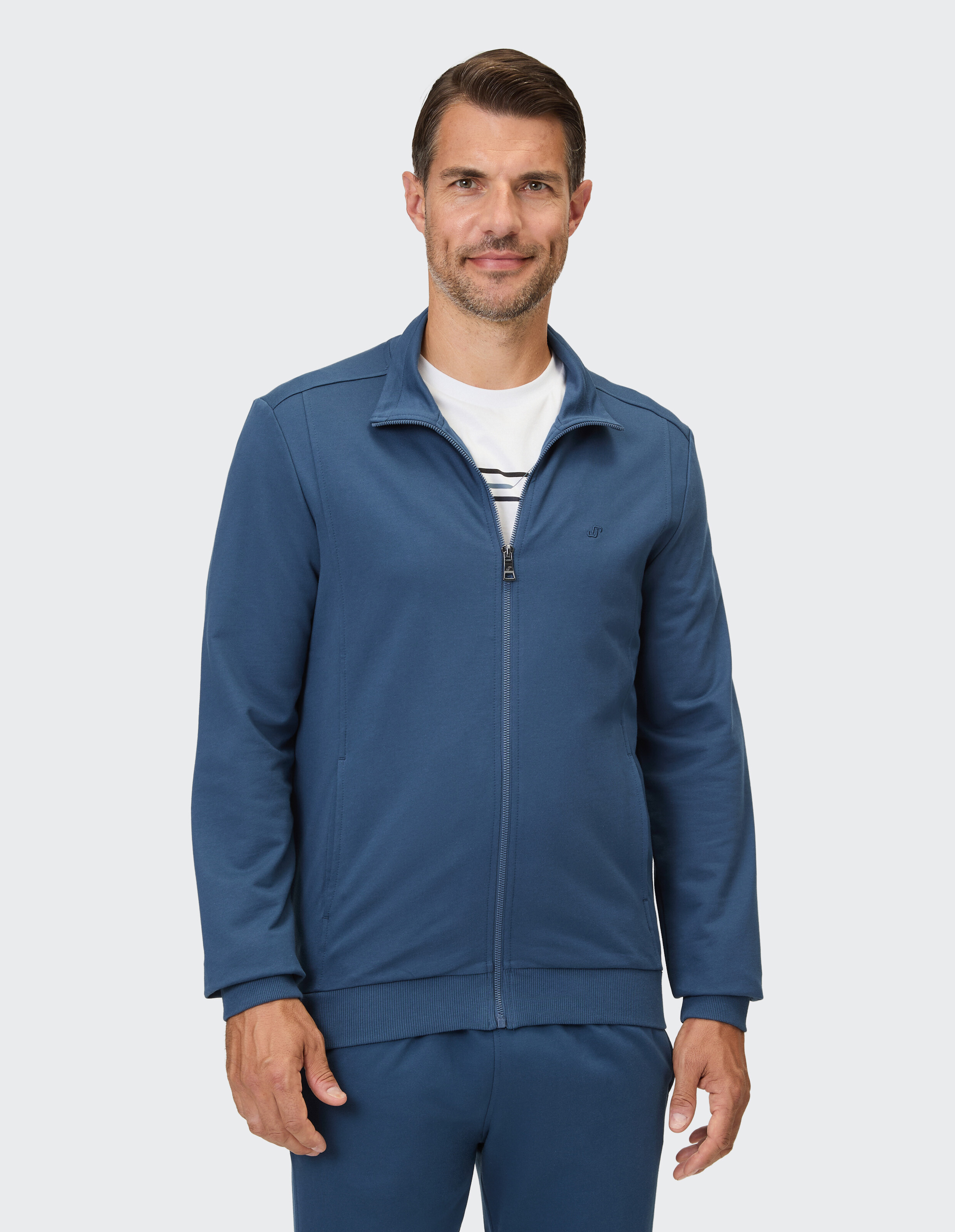 Ein Mann trägt eine blaue Trainingsjacke mit Reißverschluss und einen gestreiften Kragen.