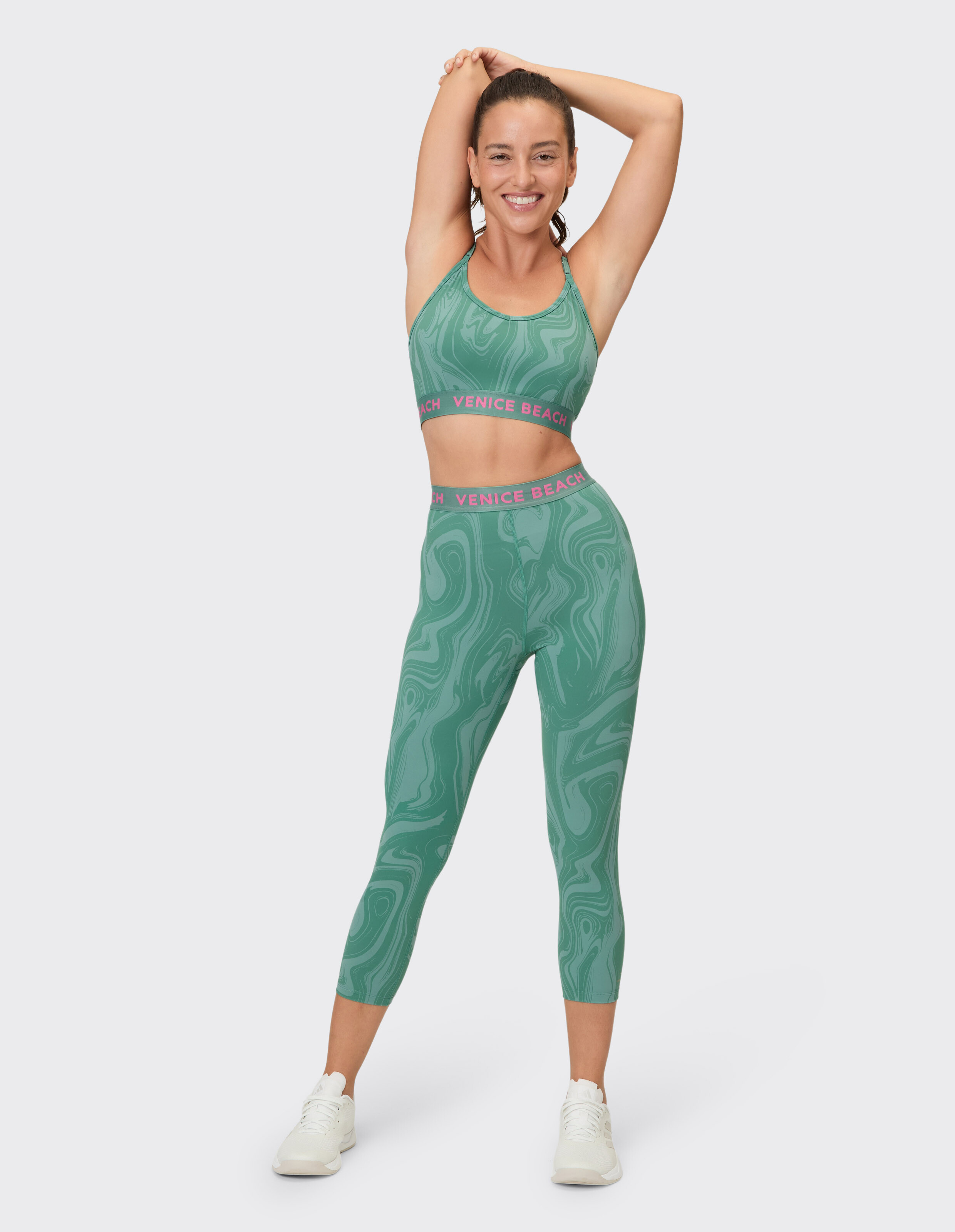 Modell in grün gemustertem Sport-BH und Leggings, perfekt für aktive Freizeitkleidung.