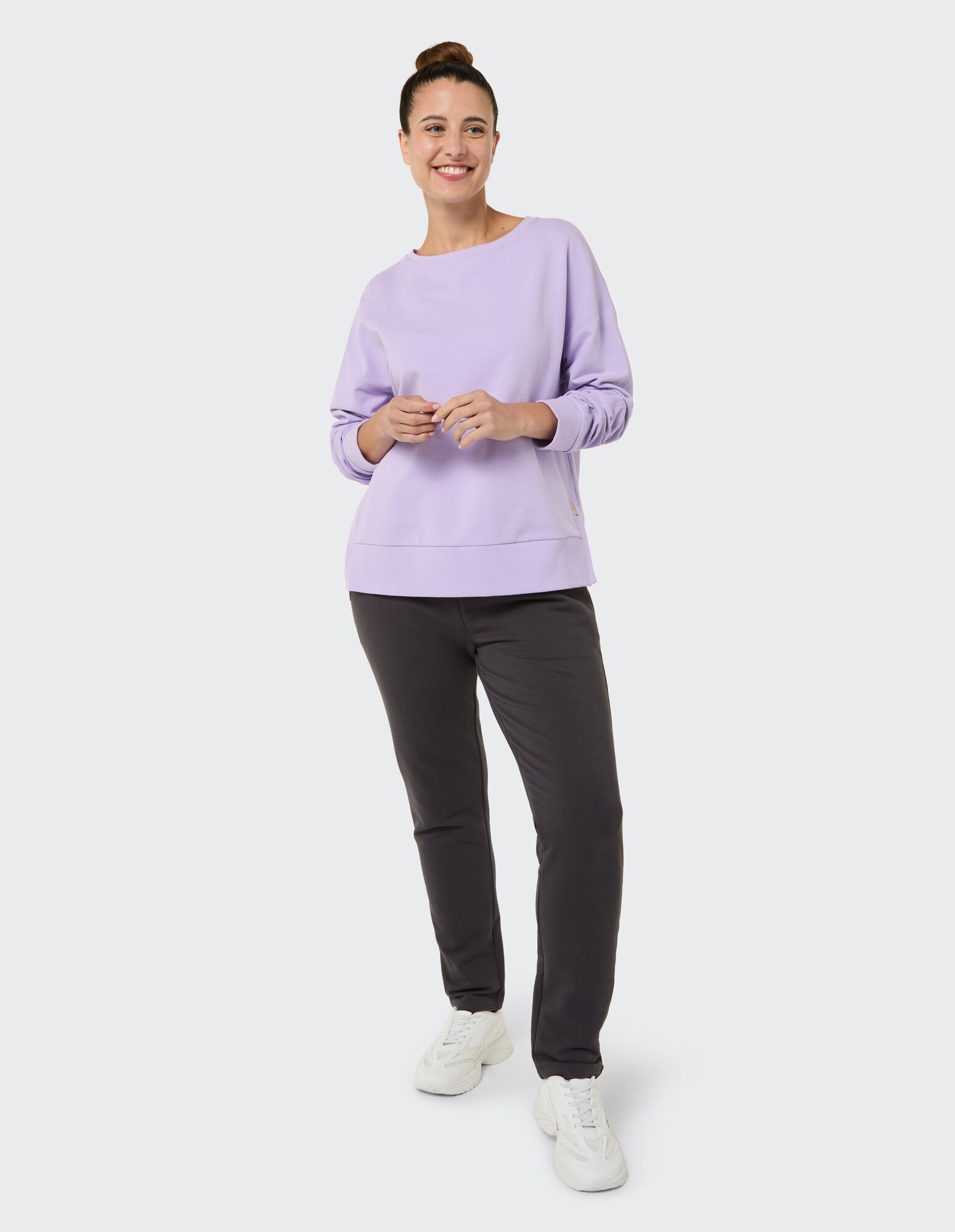 Frau in einem lila Sweatshirt und einer dunklen Hose, perfekt für Freizeitkleidung.
