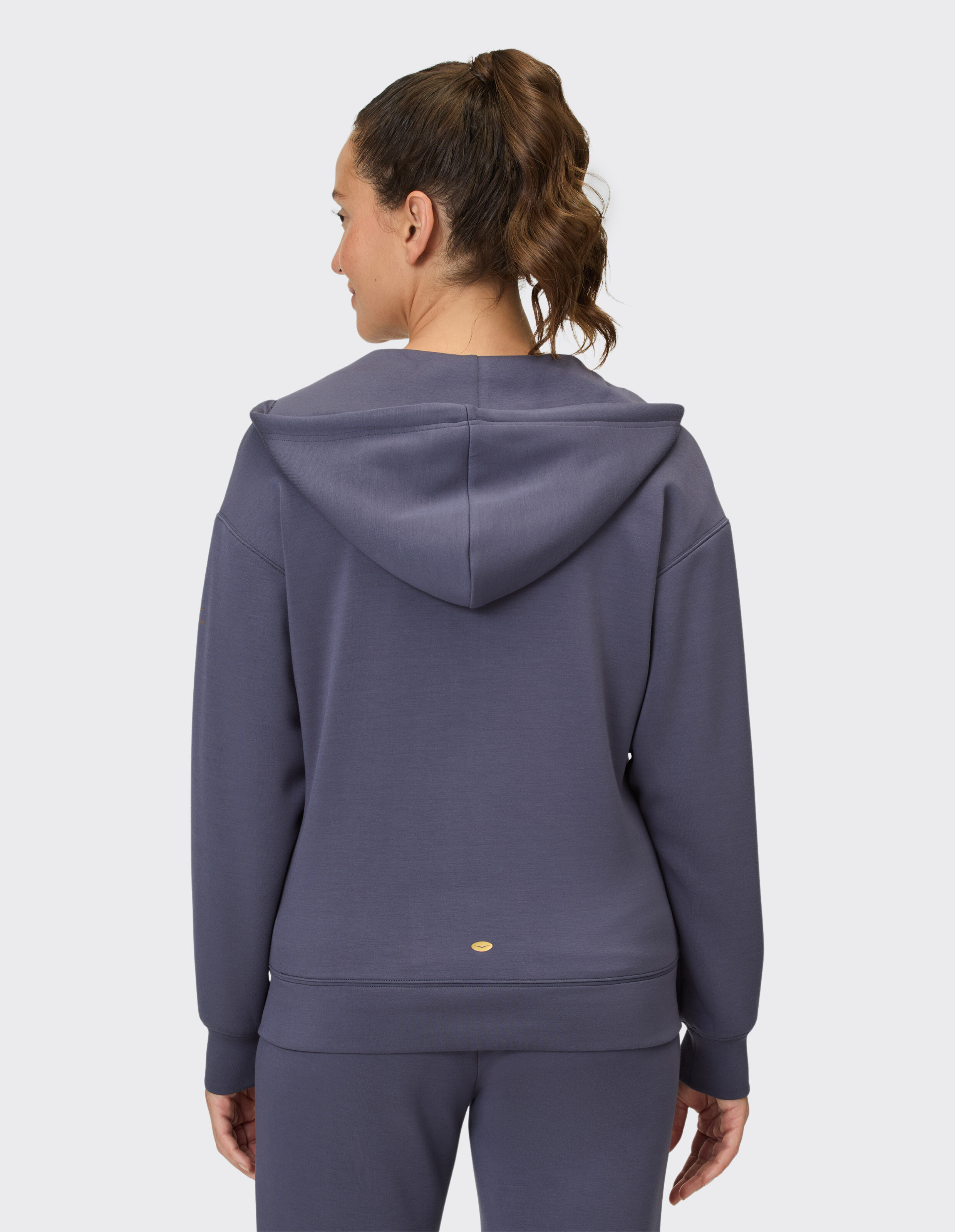 Rückansicht einer Frau, die einen kuscheligen lila Kapuzenpullover mit Kapuze und lockerer Passform trägt, ideal für Freizeitkleidung.