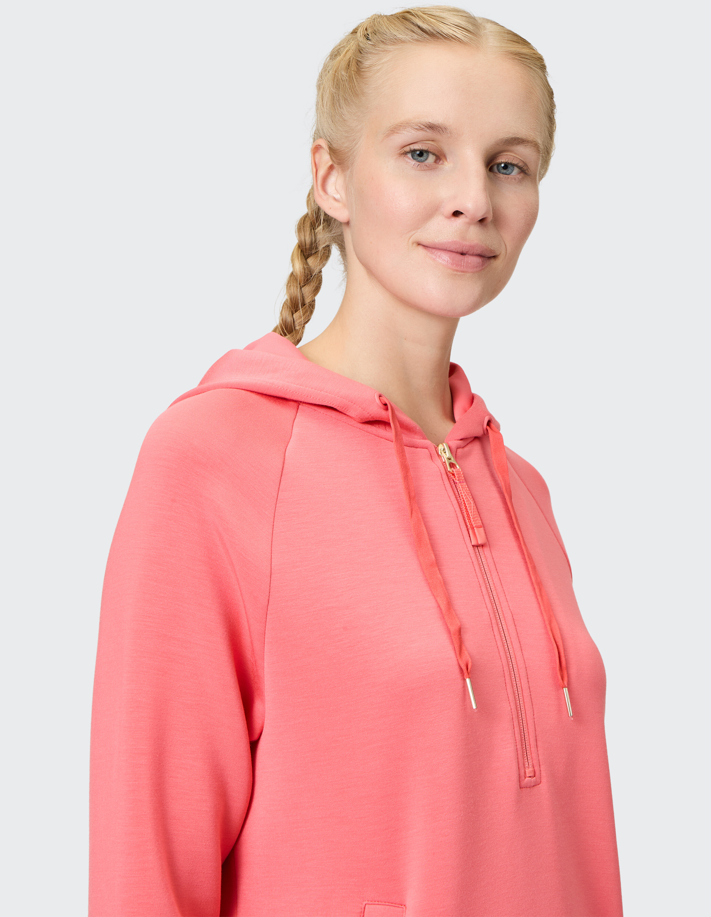 Nahaufnahme einer Frau in einem rosa Kapuzenpullover mit Reißverschluss, die einen lässigen und bequemen Stil zeigt.