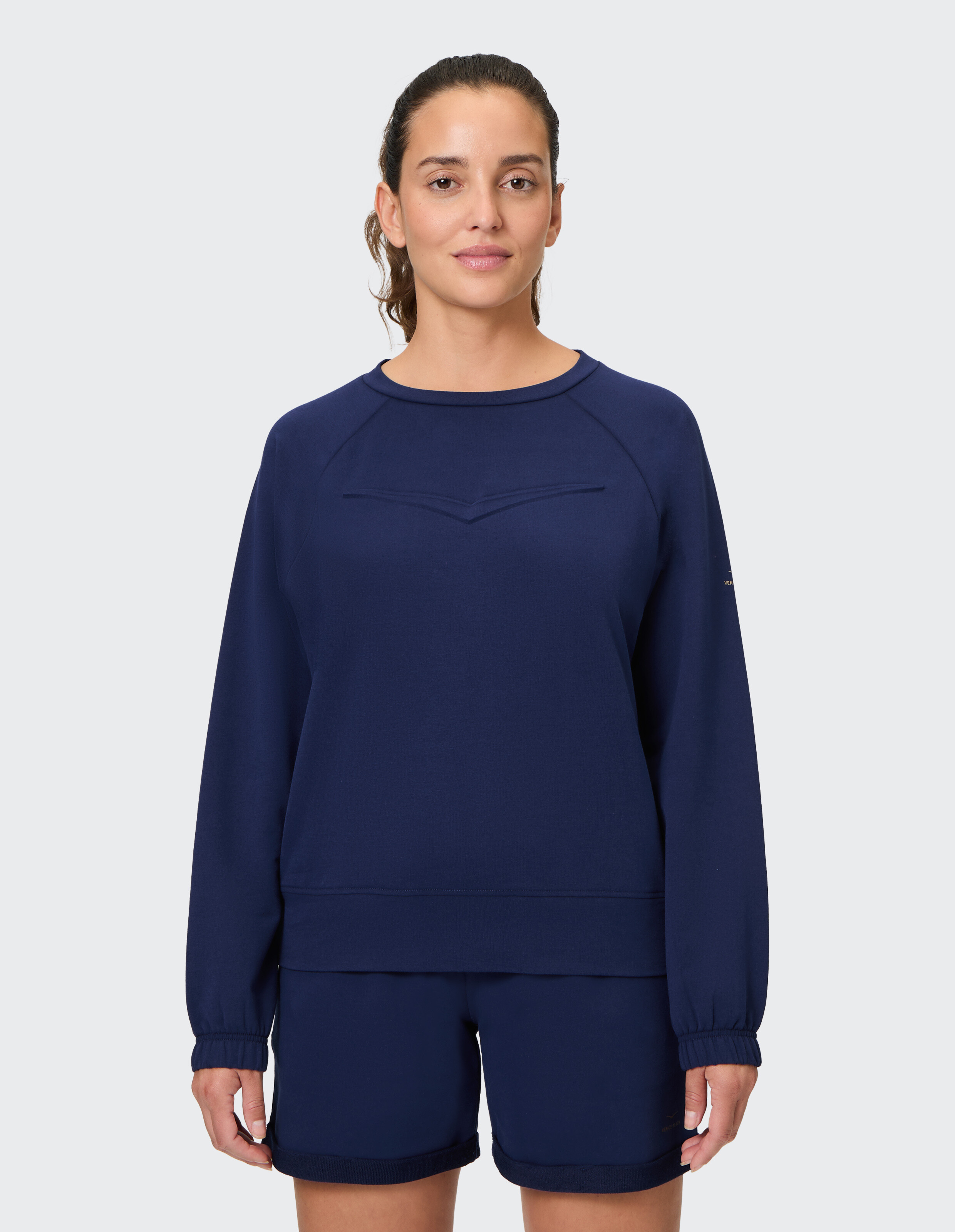 Frau trägt ein gemütliches marineblaues ELBSAND-Sweatshirt für lässige Lounge-Kleidung.