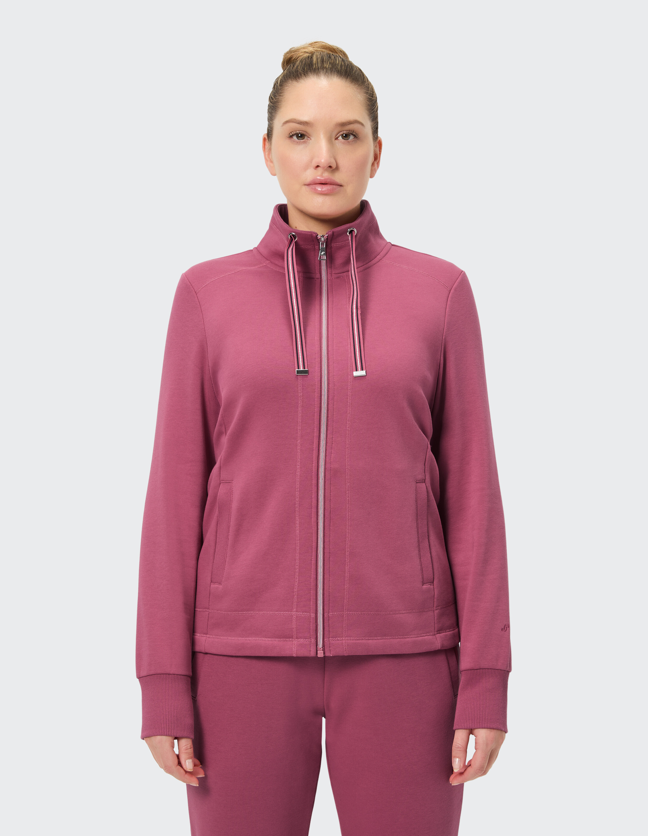Frau in einer kuscheligen rosa Jacke mit Reißverschluss, perfekt für Freizeitkleidung oder zum Faulenzen.