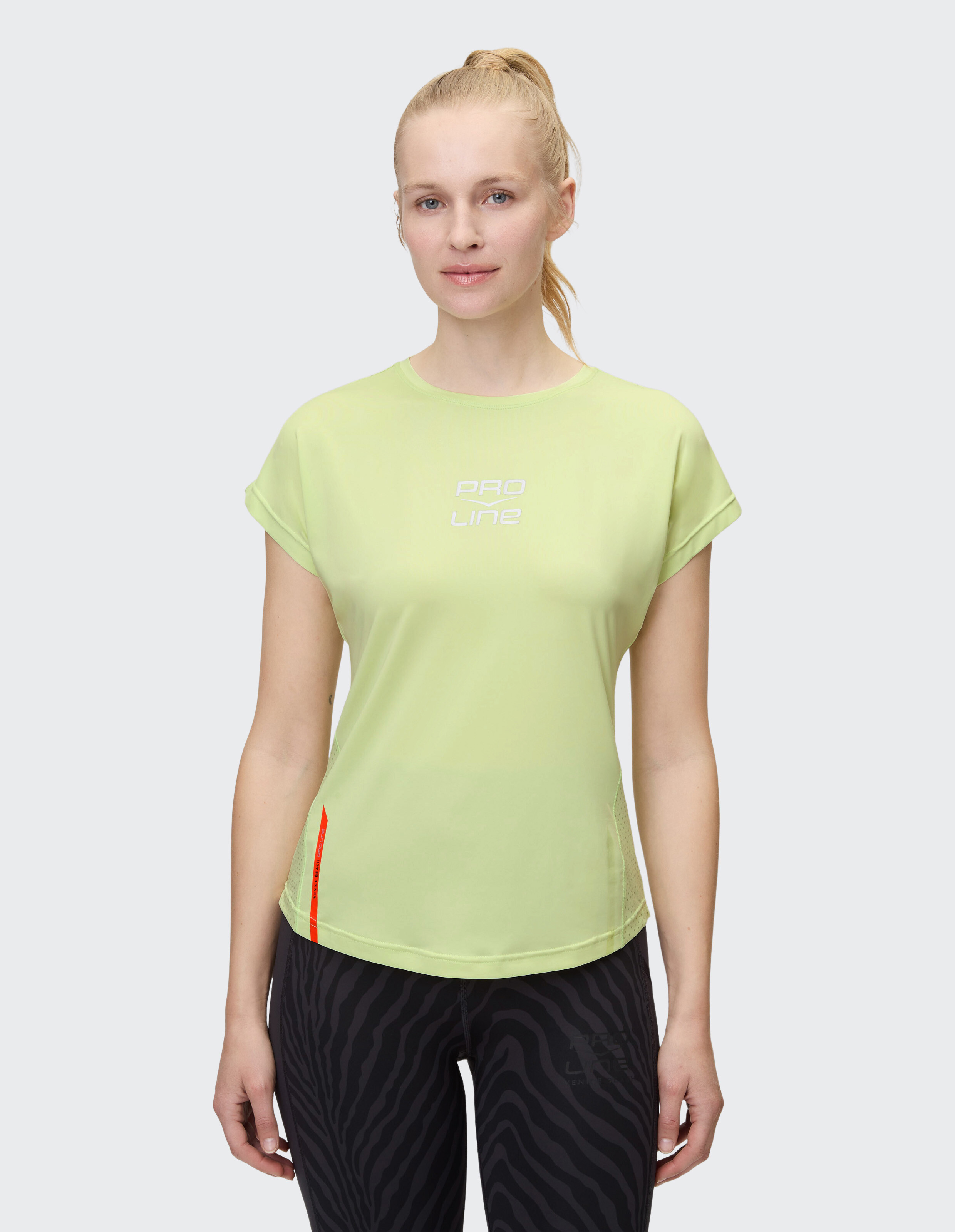 Frau trägt ein lindgrünes kurzärmliges Sport-T-Shirt mit Pro Line-Branding.