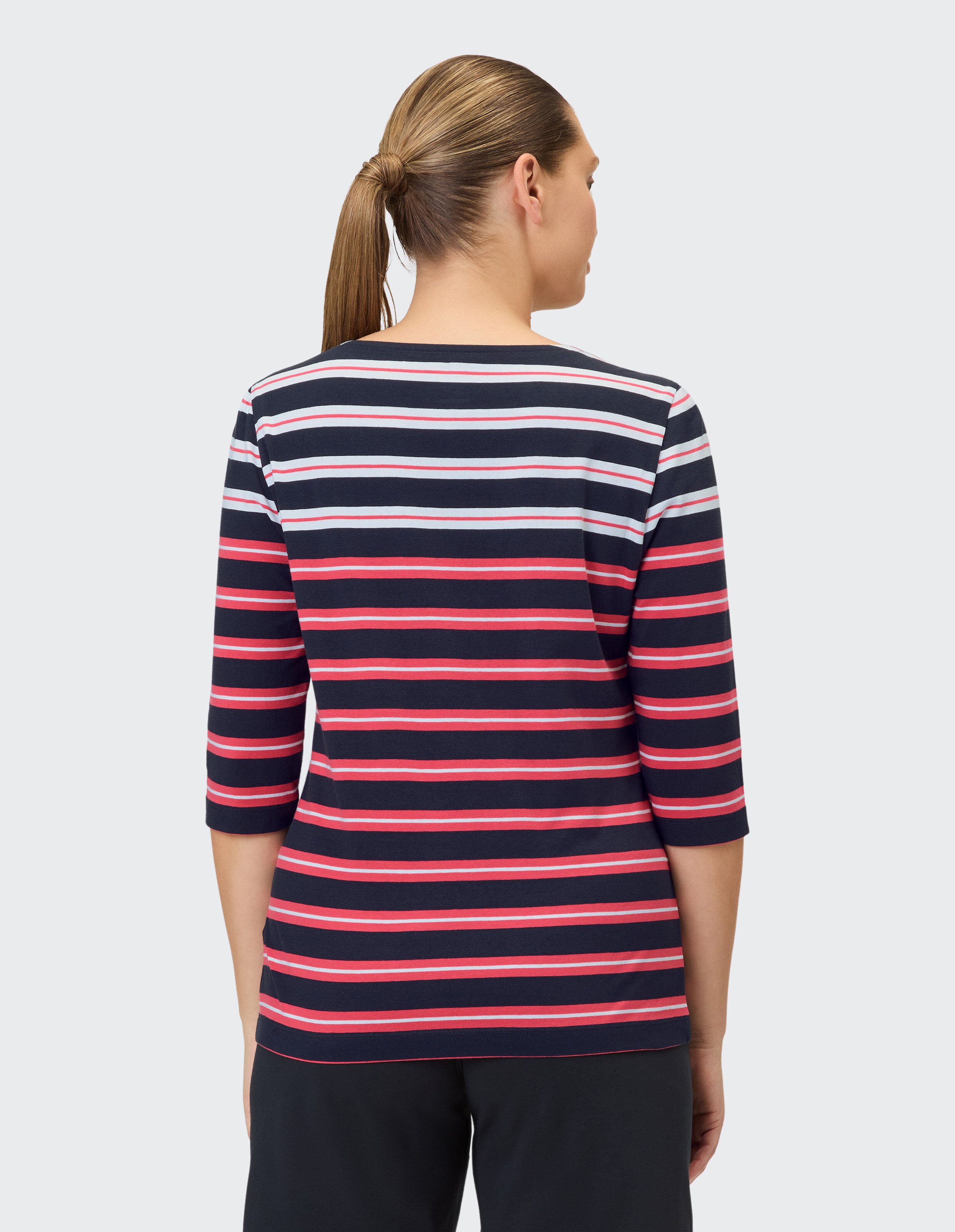 Rückansicht einer Frau in einem gestreiften marineblauen und roten Freizeitoberteil mit Dreiviertelärmeln.