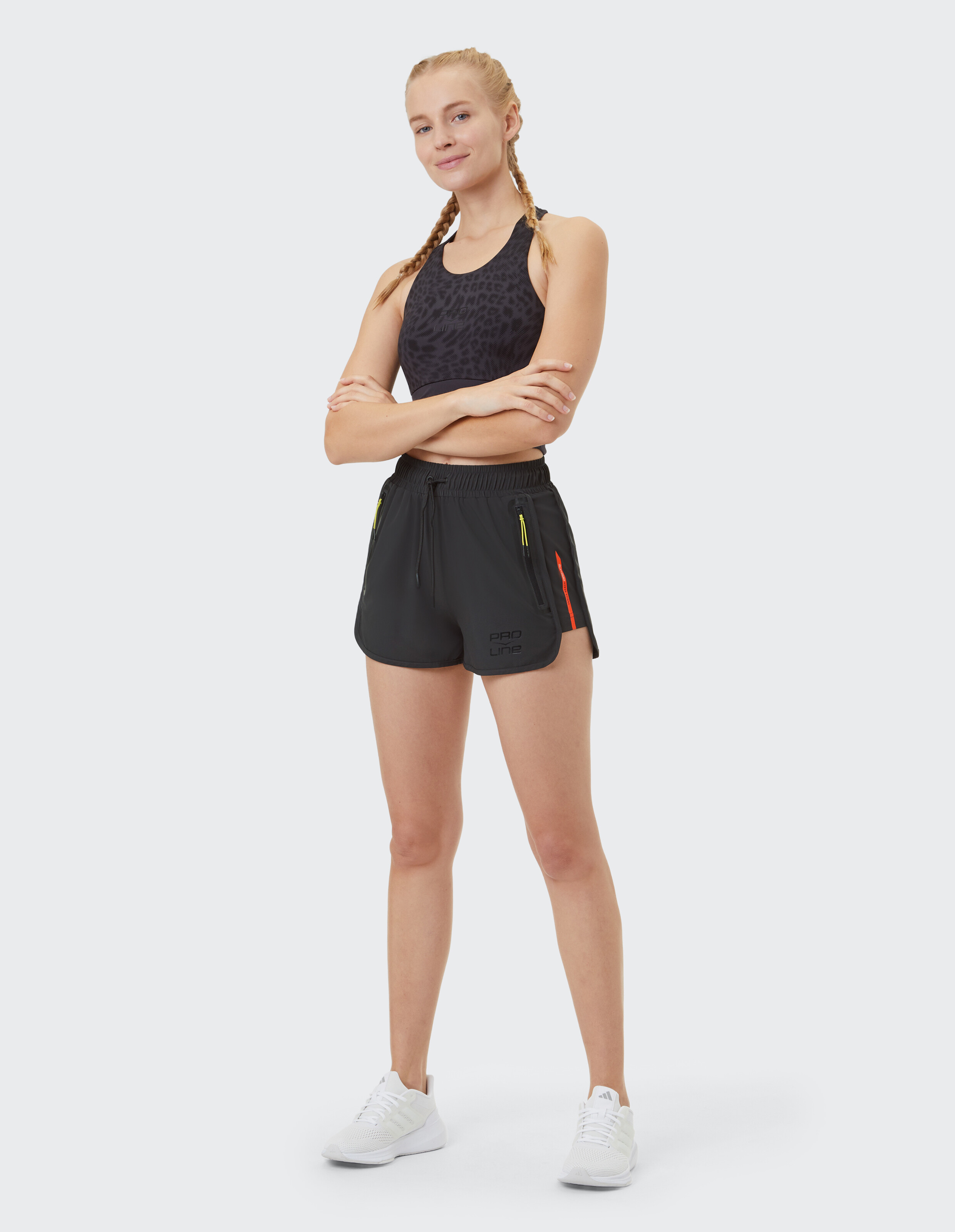 Frau trägt einen schwarzen Sport-BH mit Leopardenmuster und schwarze Sportshorts.
