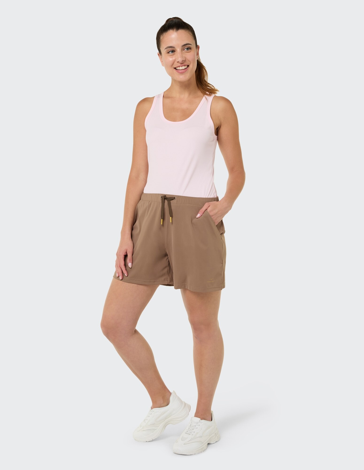 Frau in einem rosa Tanktop und braunen Shorts, lässig gestylt.