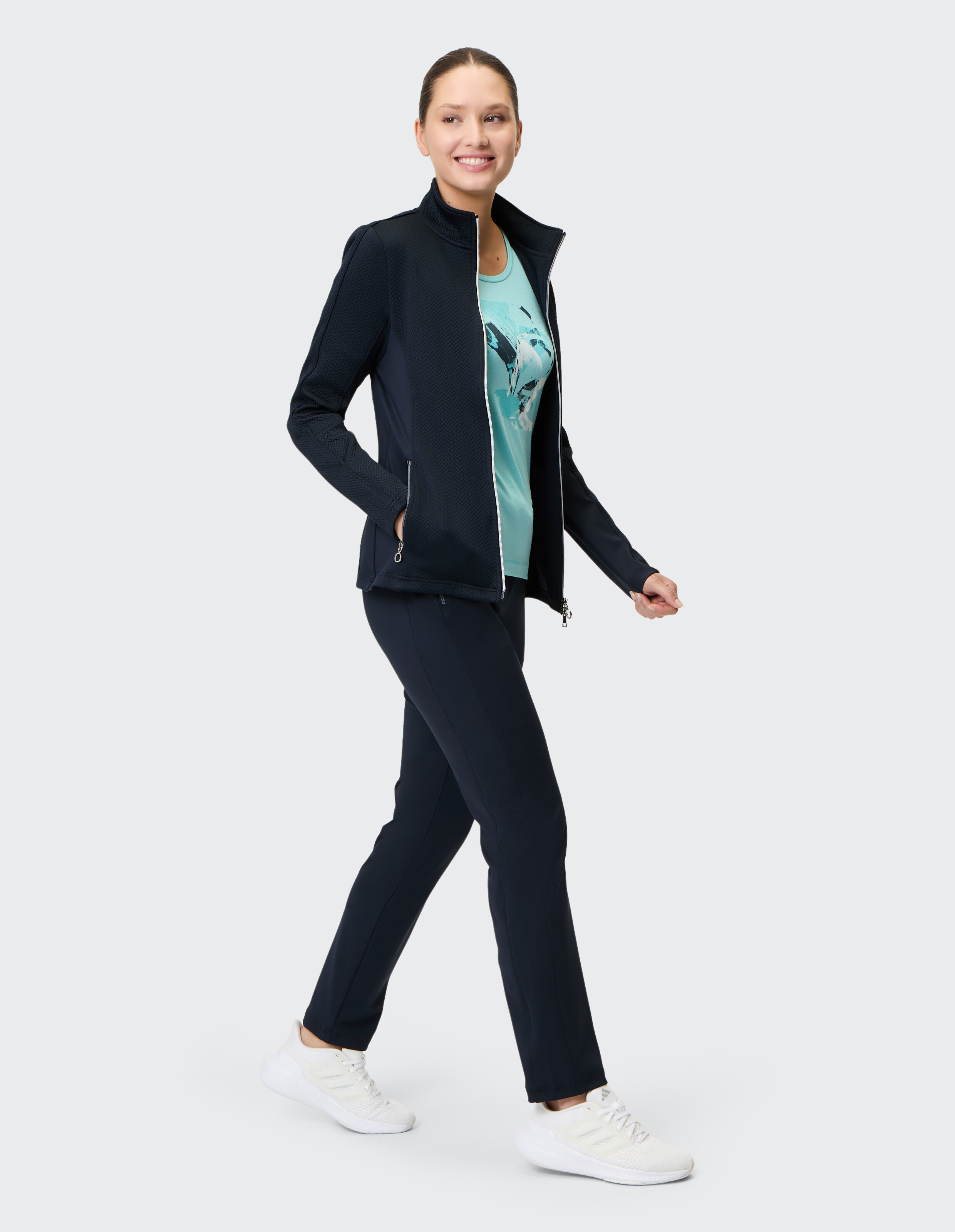 Frau trägt eine dunkelblaue Jacke mit Reißverschluss und eine passende Hose, perfekt für Freizeitreisen oder zum Faulenzen.