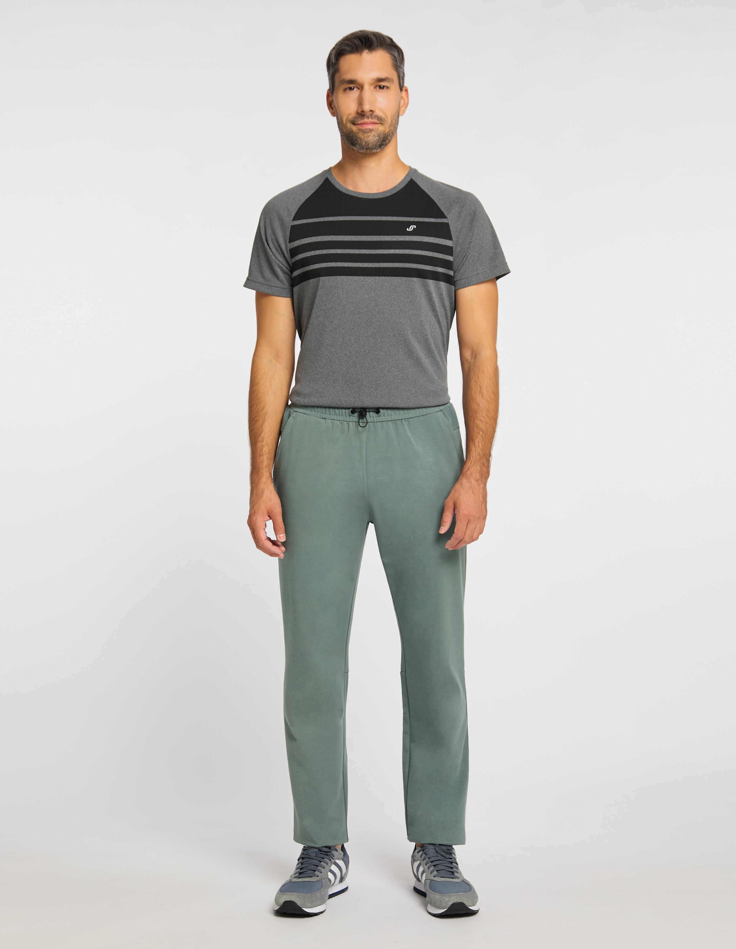 Mann trägt ein grau gestreiftes T-Shirt und eine salbeigrüne Freizeit-Jogginghose für einen bequemen Look.