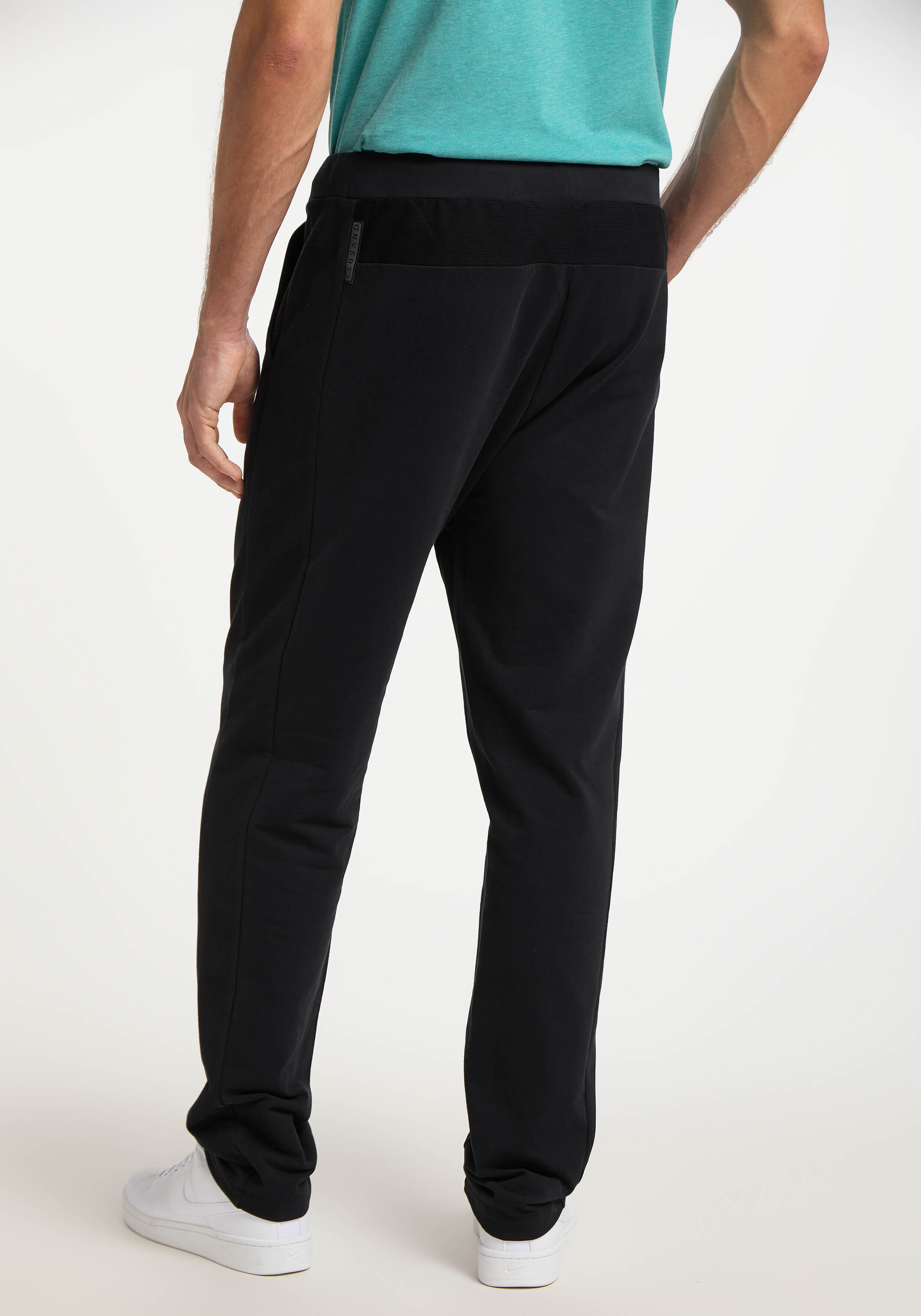 Mann trägt bequeme schwarze Freizeit-Jogginghose, Rückansicht, ideal zum Faulenzen oder Reisen.