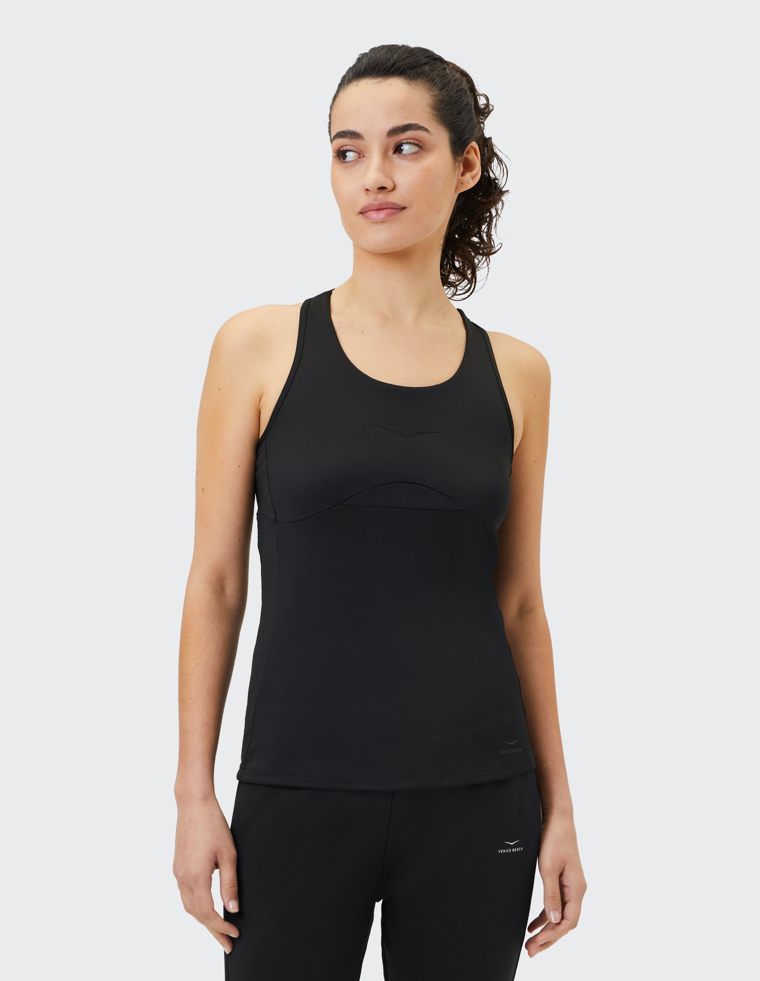 Frau trägt ein schwarzes Jizelle-Tanktop von Venice Beach für lässige, bequeme Aktivkleidung.