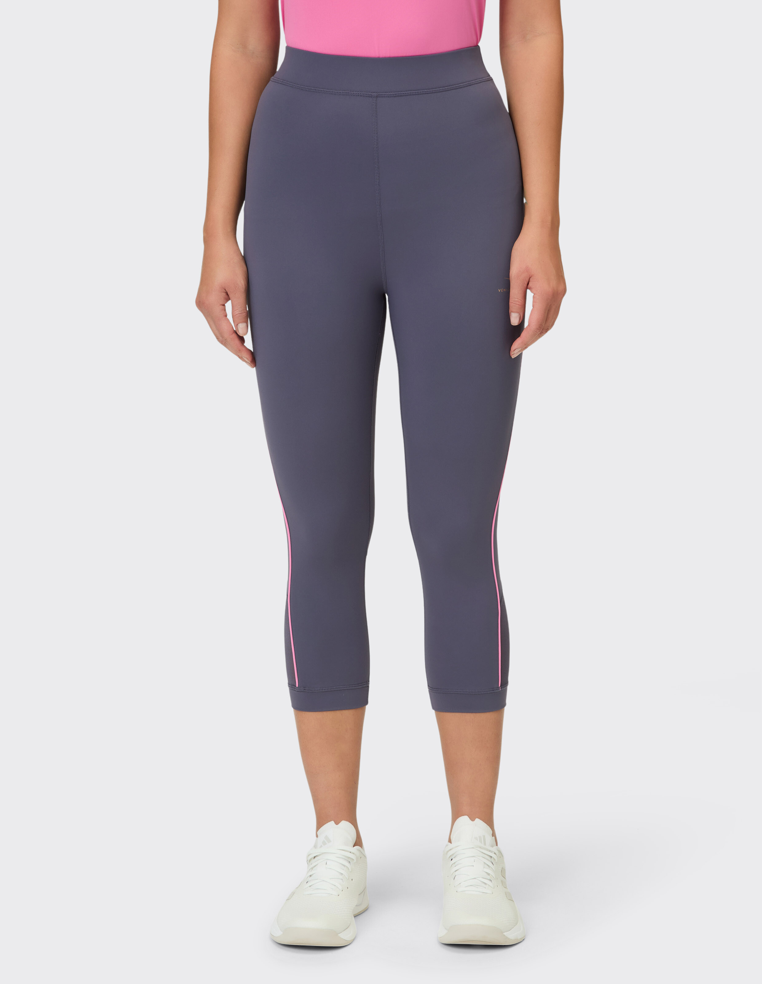 Frau trägt graue Capri-Leggings mit rosa Seitenstreifen für lässige Sportkleidung.