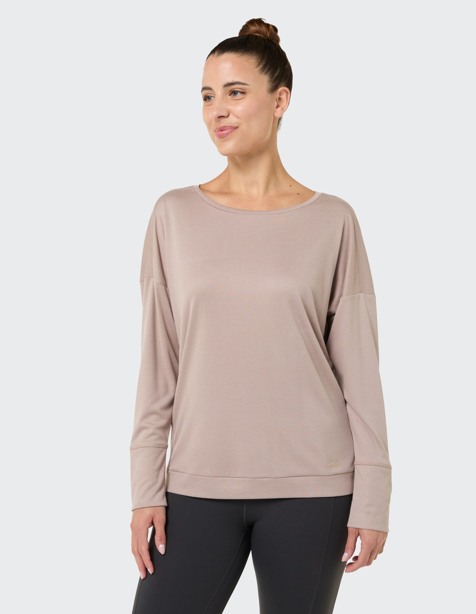 Frau in einem kuscheligen beigen Langarmshirt, perfekt für Freizeitkleidung und zum Faulenzen.