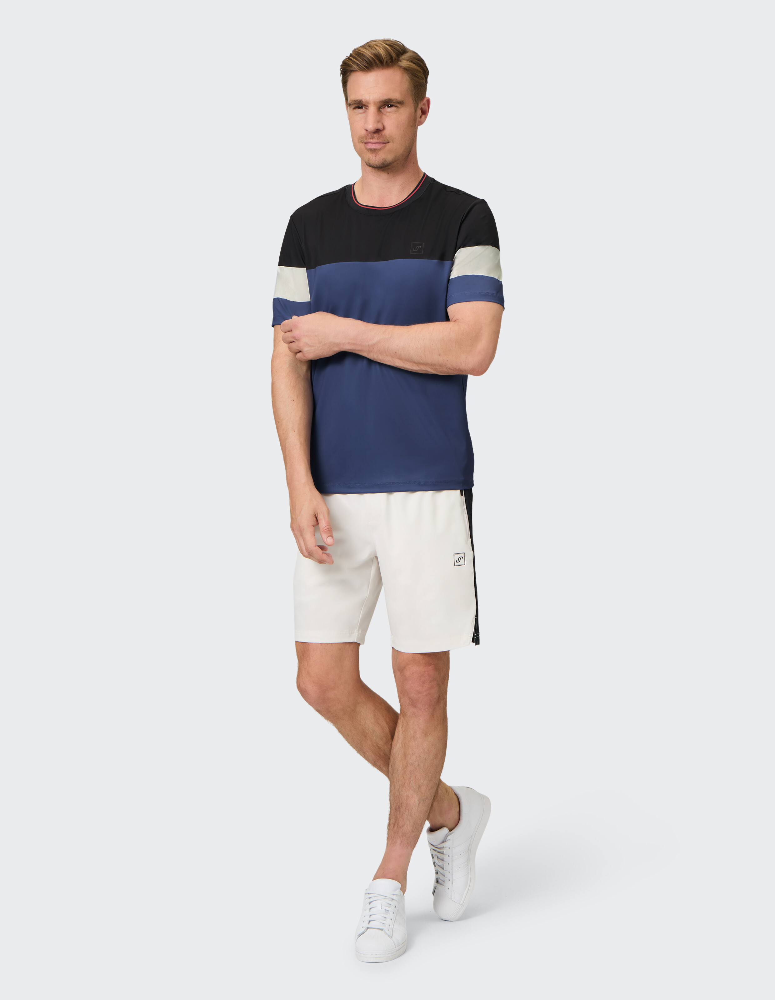 Mann in einem farbblockierten T-Shirt und weißen Shorts, ideal für Freizeitausflüge.
