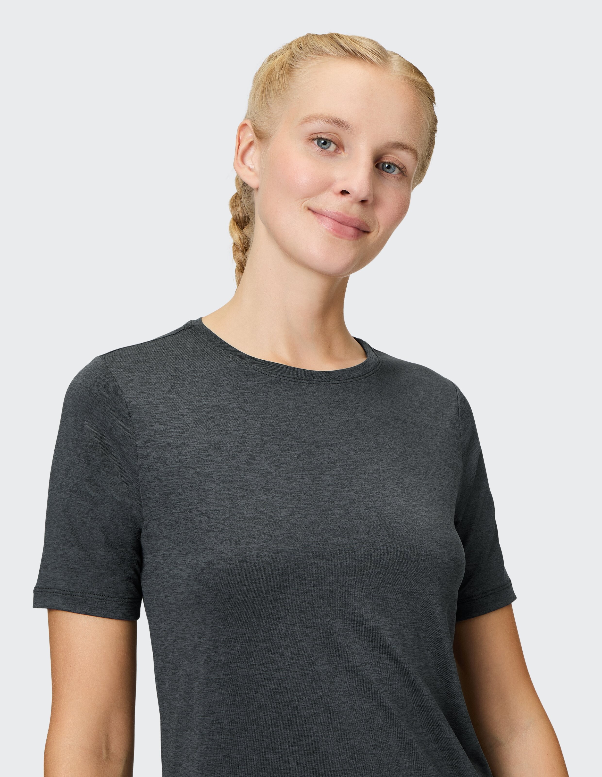 Frau trägt ein gemütliches dunkelgraues, kurzärmeliges Freizeit-T-Shirt vor einem schlichten Hintergrund.