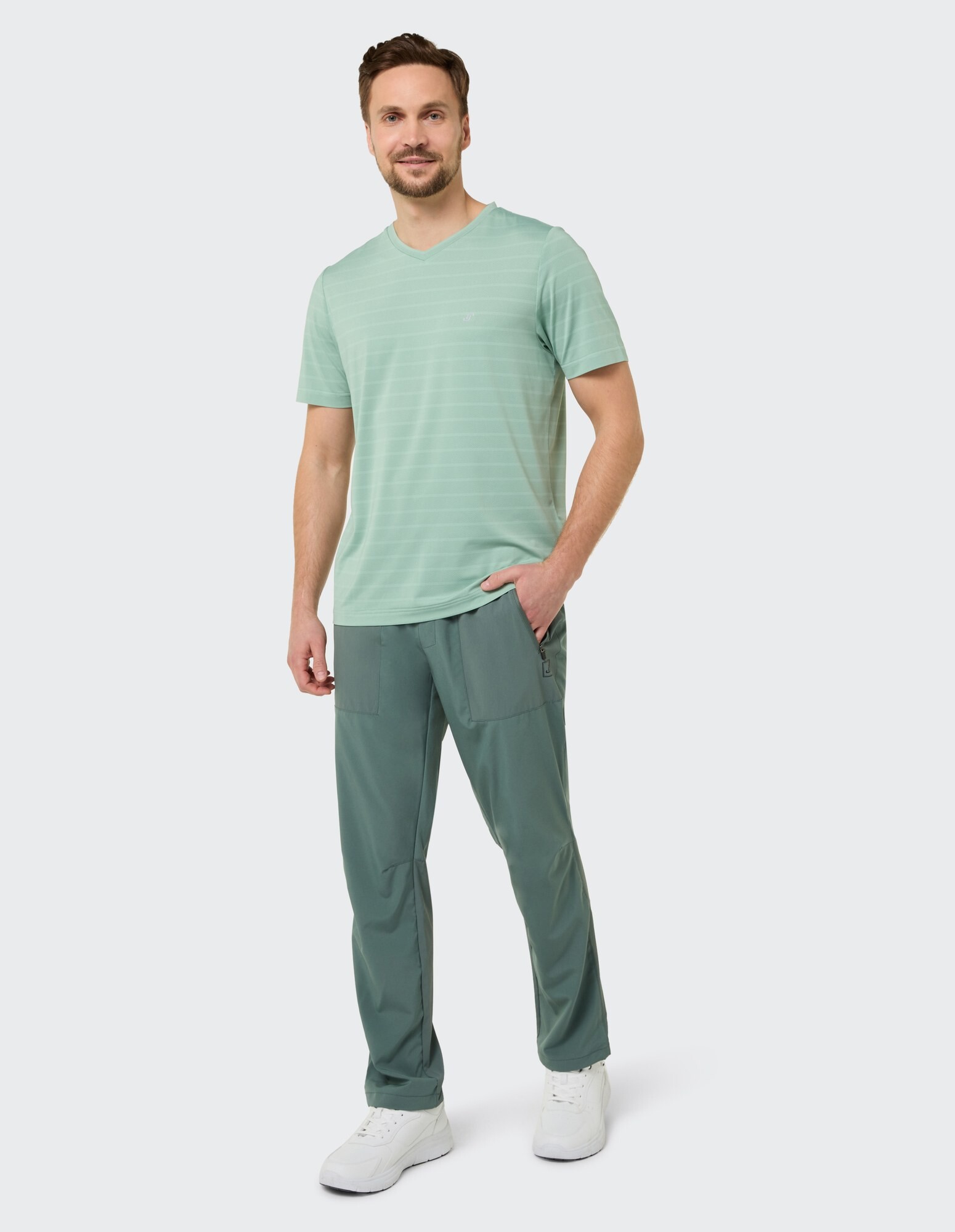 Mann in einem mintgrünen, gestreiften T-Shirt mit V-Ausschnitt und einer grünen Freizeithose, bequem gestylt.