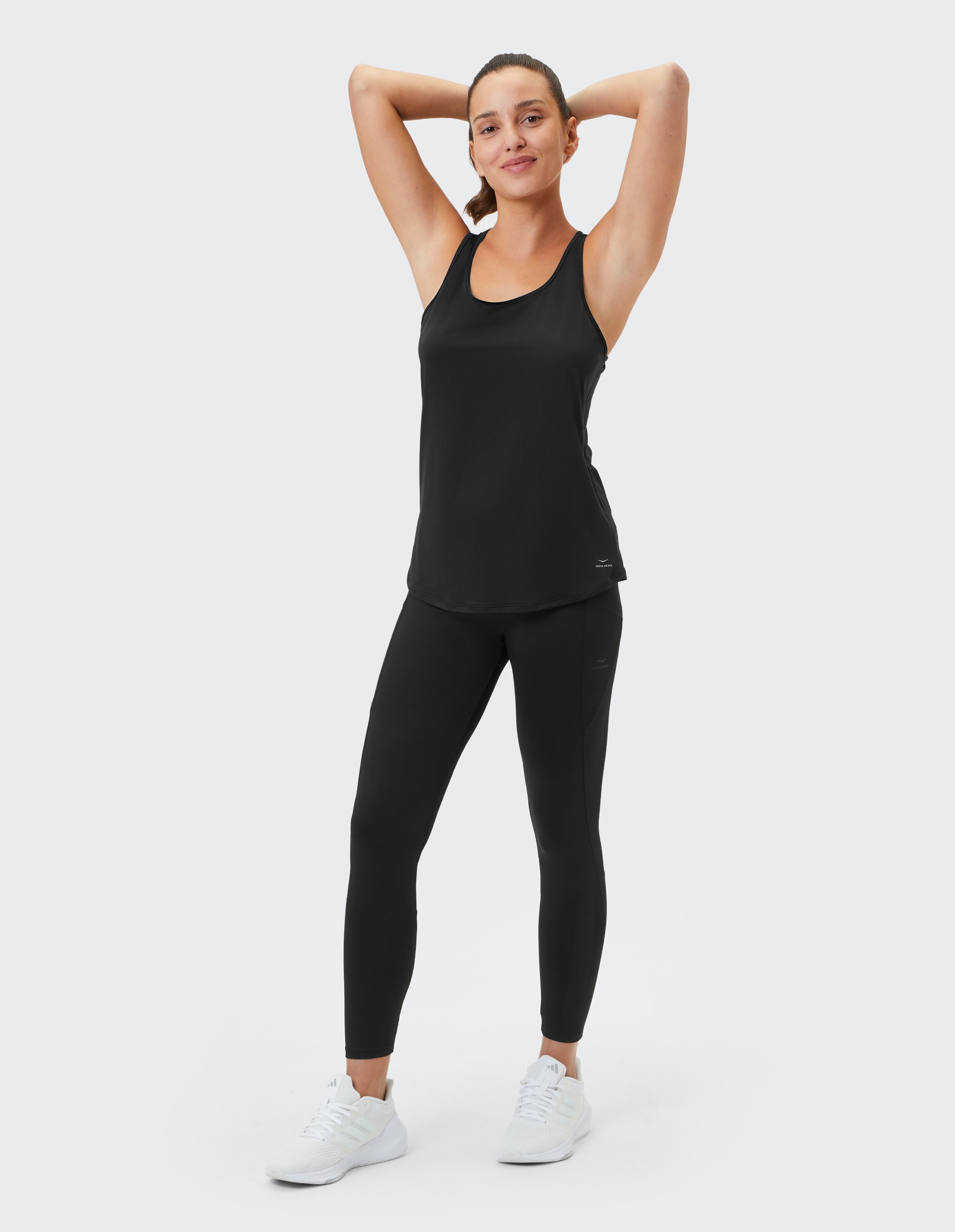 Frau trägt ein schwarzes Tanktop und passende Leggings für einen lässigen, sportlichen Stil.