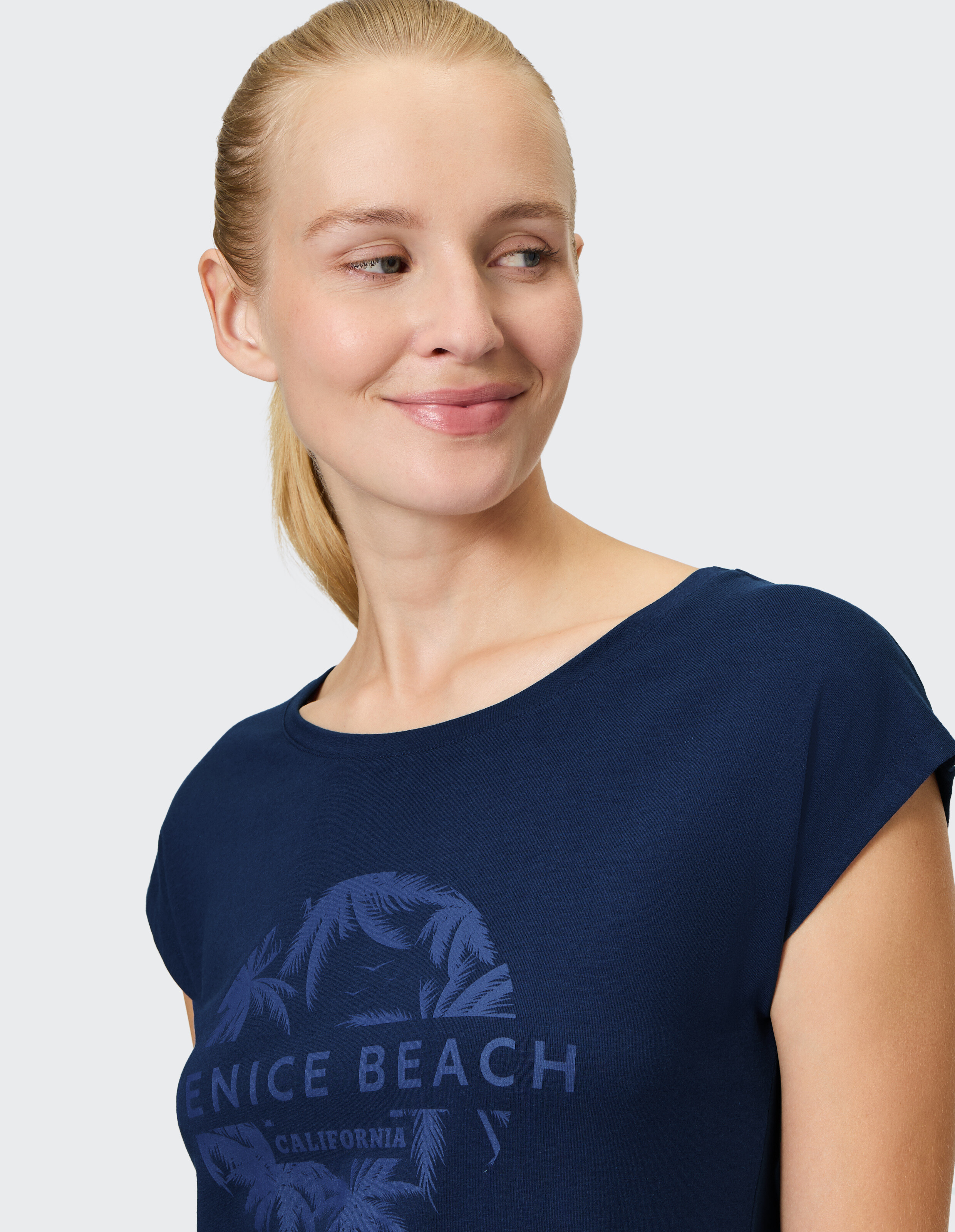 Nahaufnahme einer Frau in einem marineblauen T-Shirt mit „Venice Beach“-Grafik.