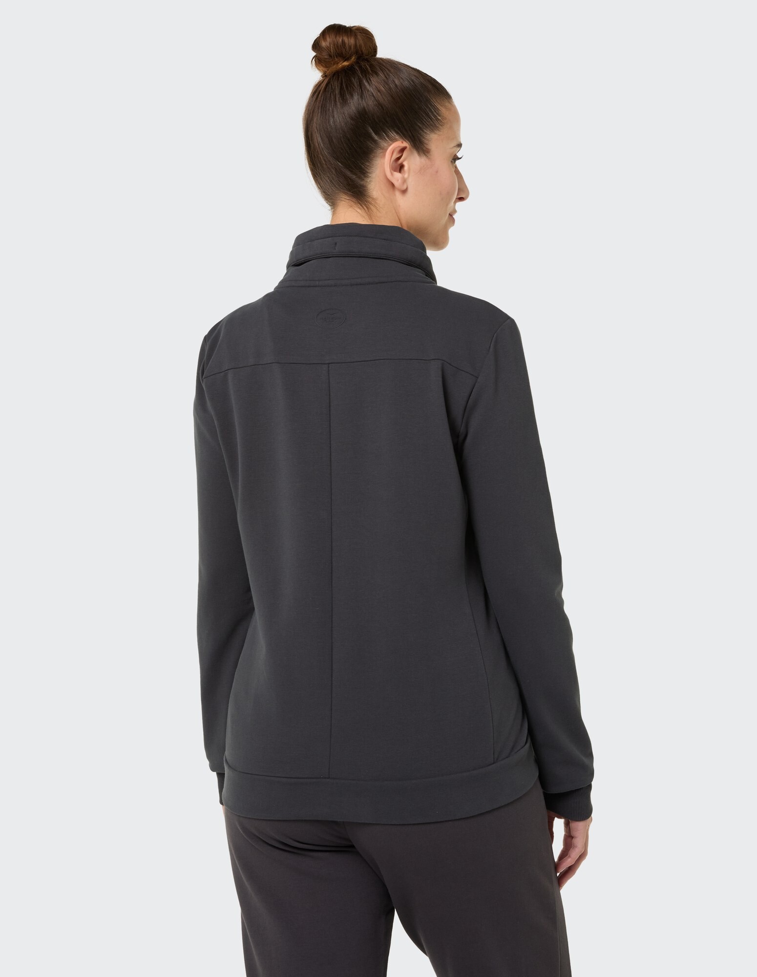 Rückansicht einer Frau in einer dunkelgrauen Freizeitjacke, perfekt zum gemütlichen Tragen.