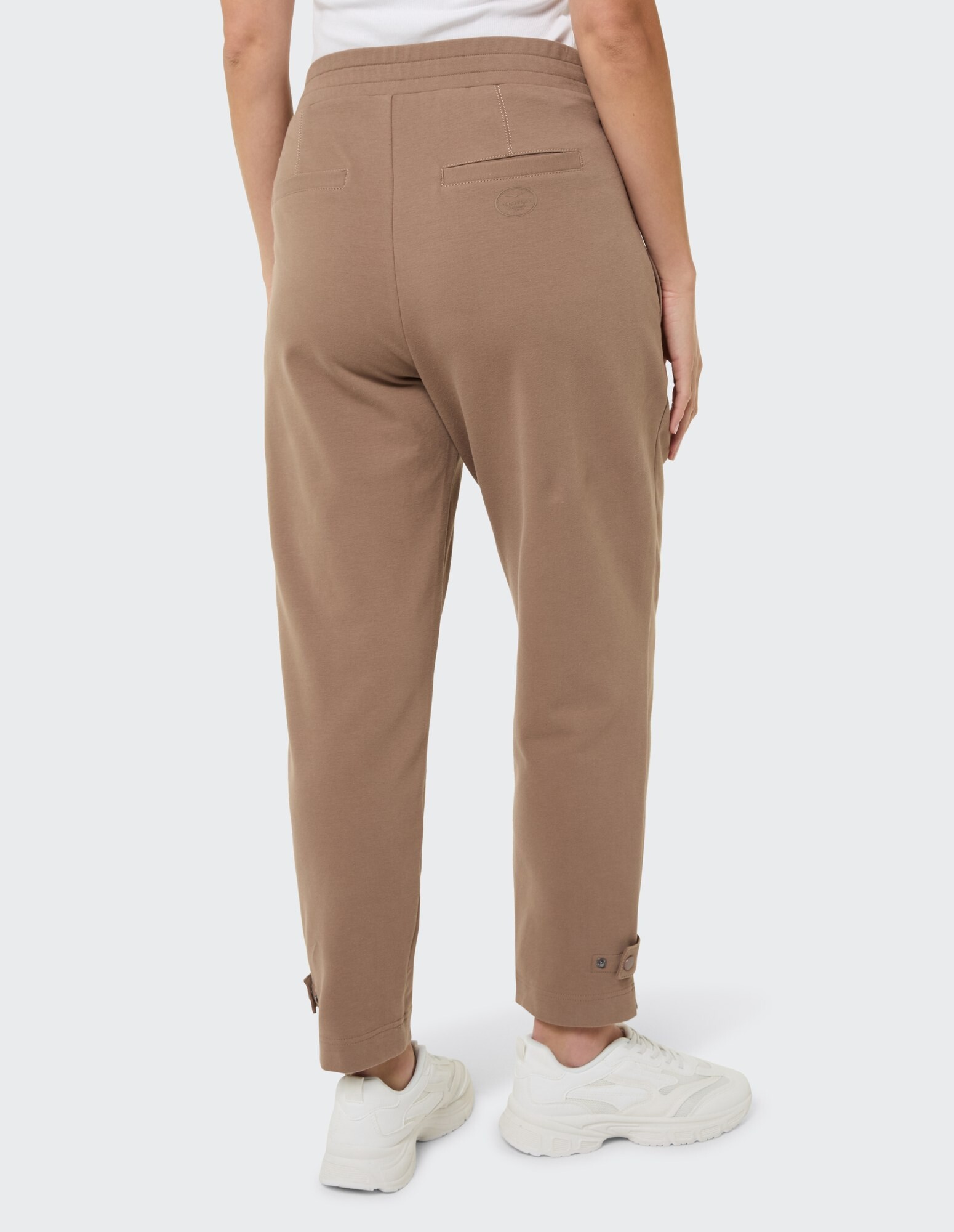 Rückansicht einer entspannten braunen Hose mit Bündchen am Saum und Taschen.