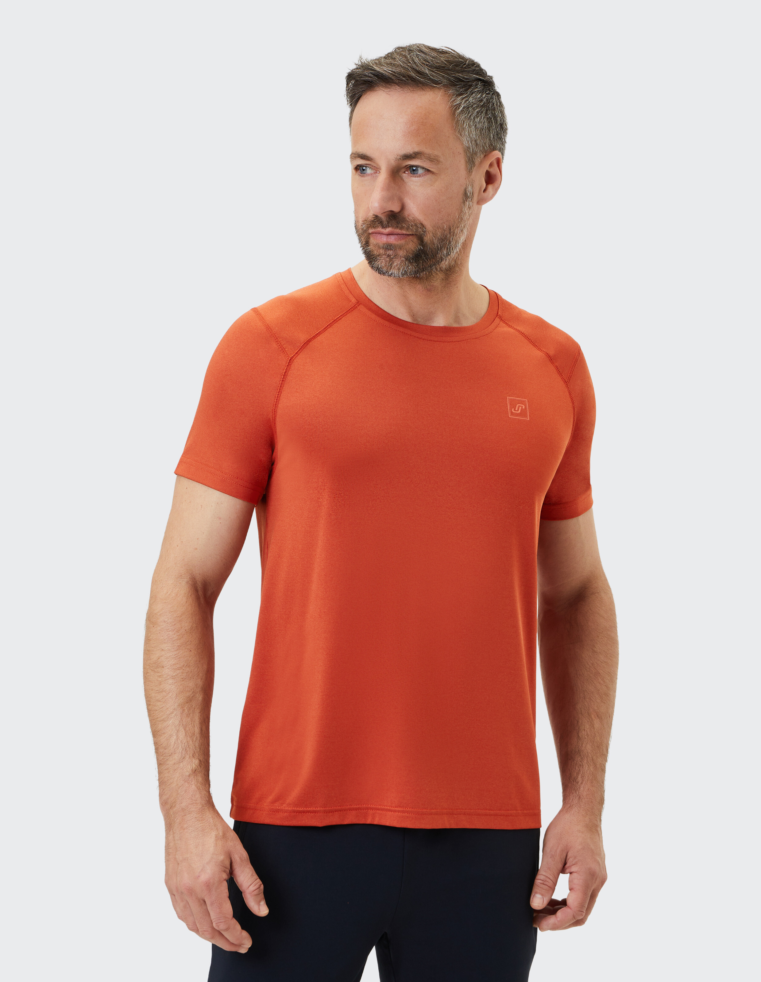 Mann trägt ein rostorangefarbenes ELBSAND-Freizeit-T-Shirt mit Raglanärmeln.