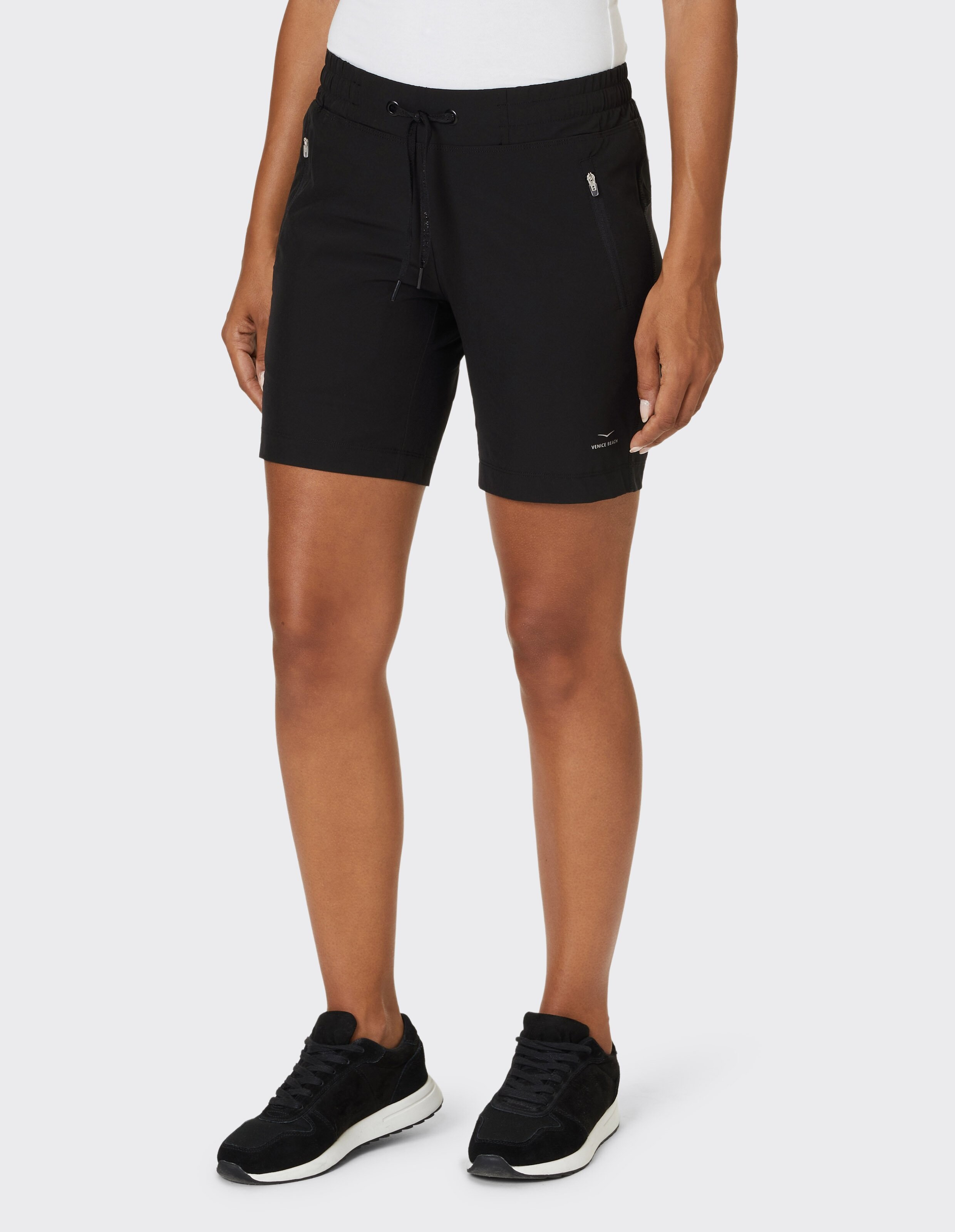 Frau trägt schwarze, lässige Sportshorts mit Kordelzug in der Taille und Seitentaschen.