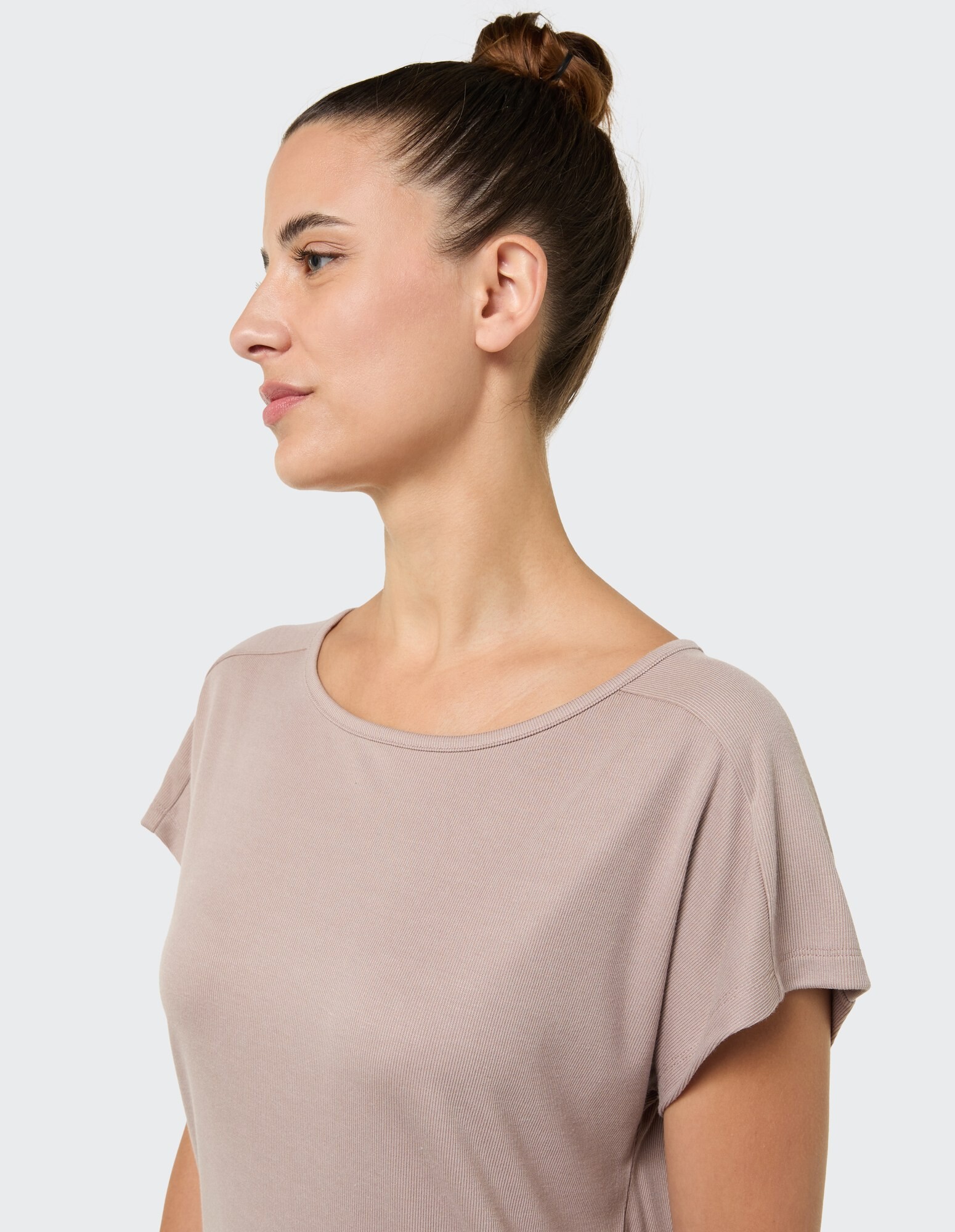 Seitenprofil einer Frau, die ein hellbraunes, locker sitzendes T-Shirt trägt.