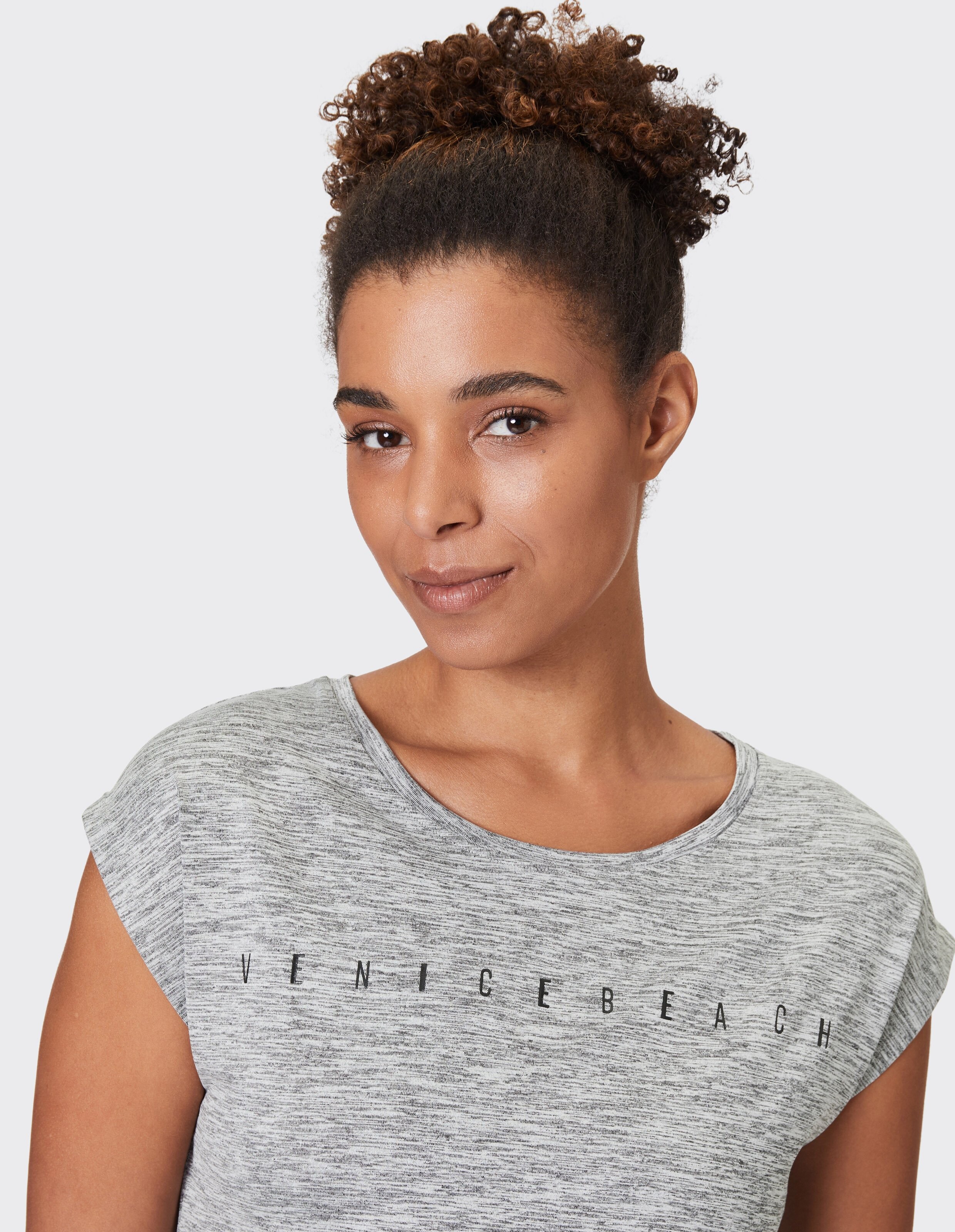 Frau trägt ein grau meliertes Venice Beach-Freizeit-T-Shirt für bequeme Loungewear.