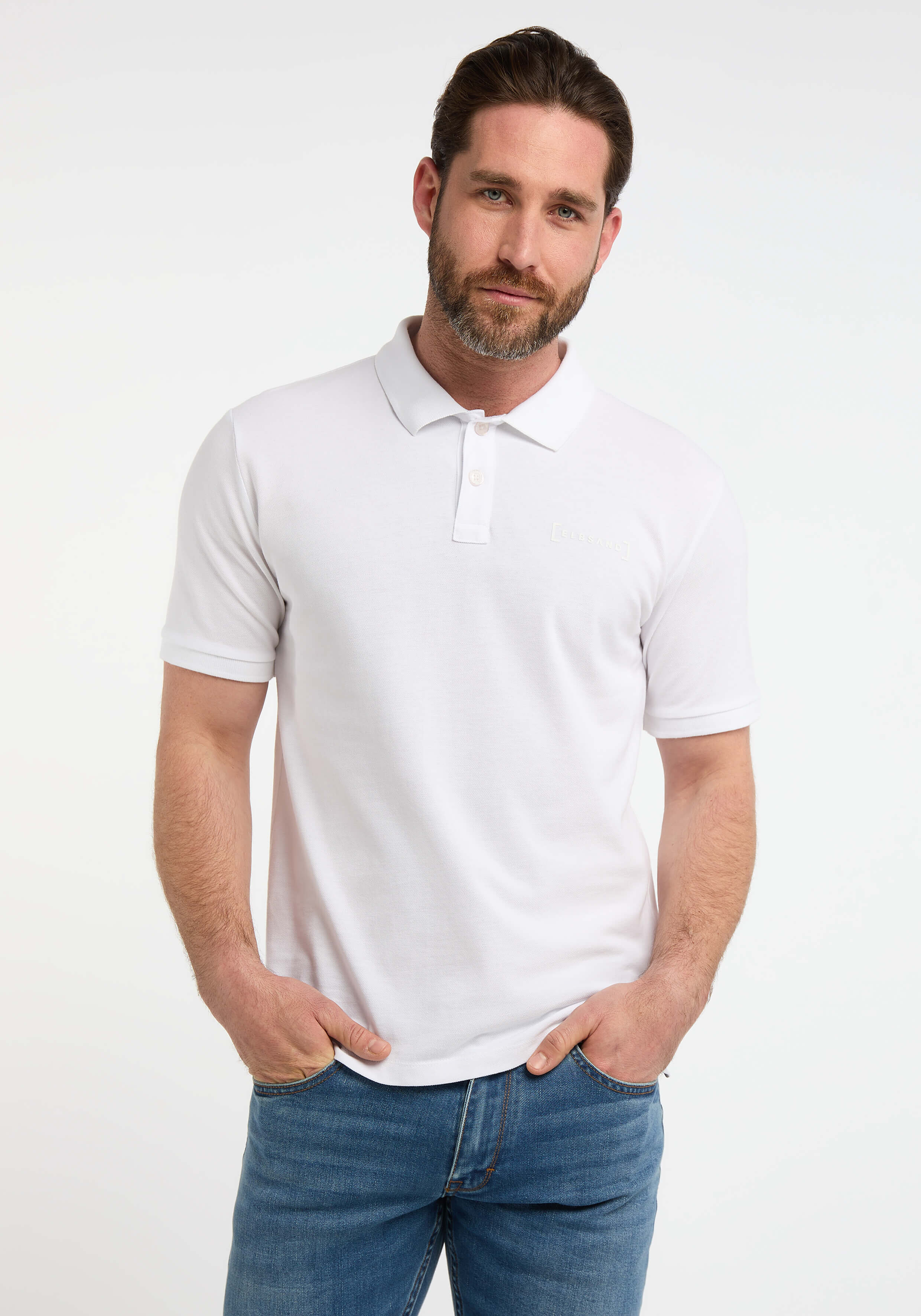 Mann trägt ein klassisches weißes ELBSAND-Poloshirt mit blauen Jeans für einen lässigen Look.