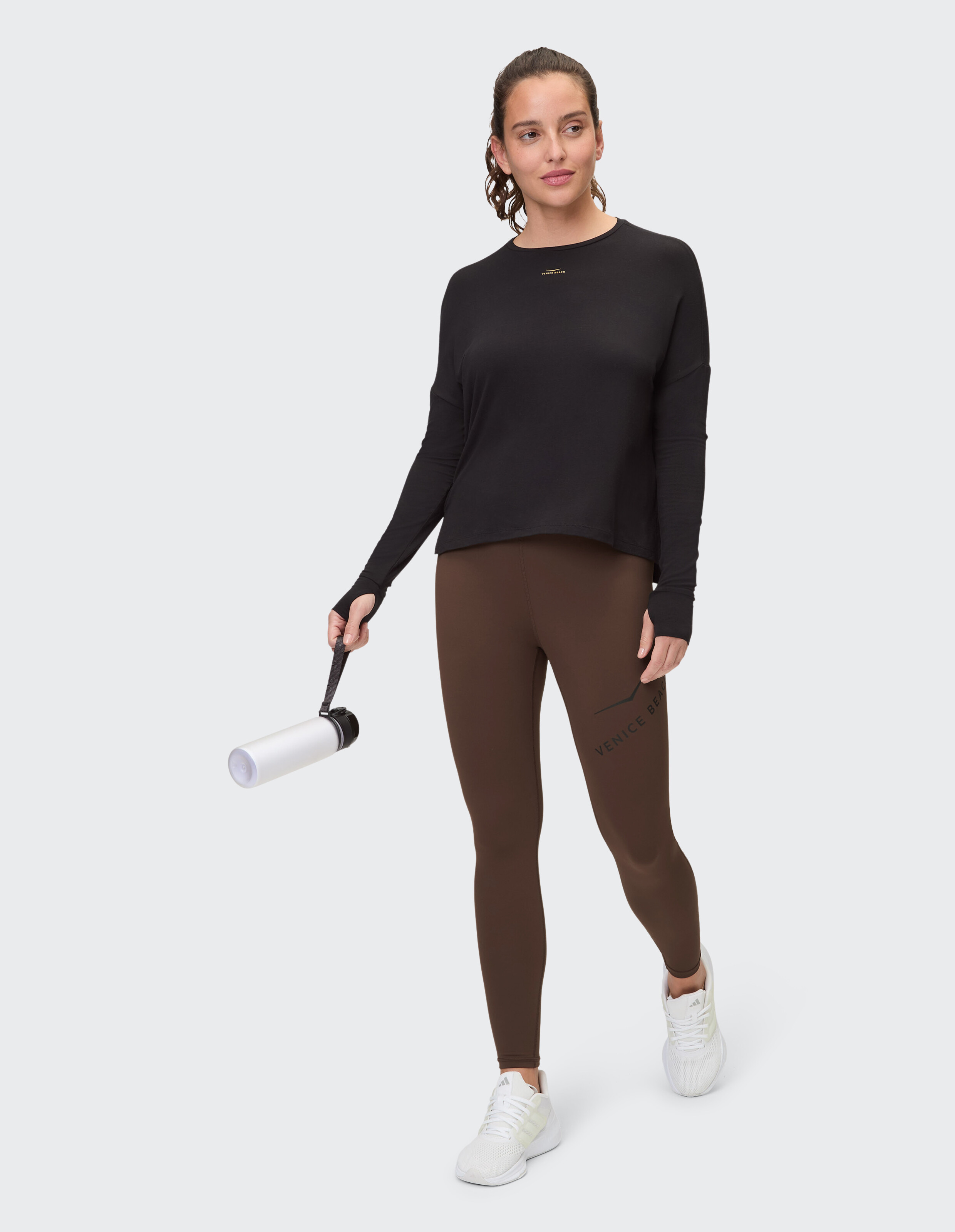 Frau trägt ein schwarzes Langarmshirt und braune Leggings für einen lässigen, sportlichen Look.