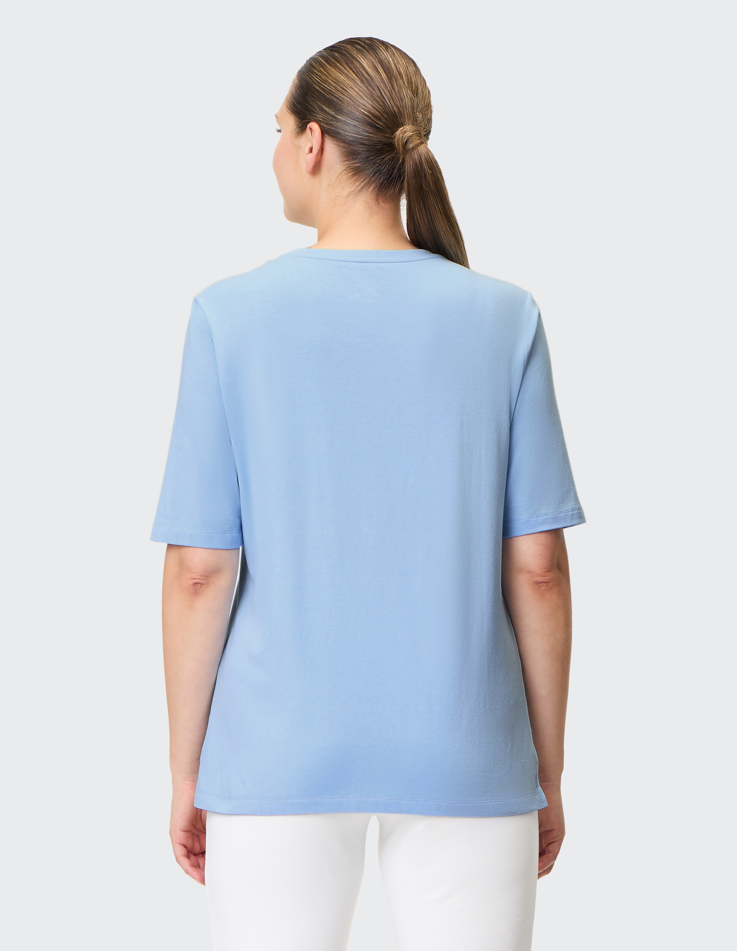 Rückansicht einer Frau, die ein hellblaues Freizeit-T-Shirt trägt, perfekt für gemütliche Alltagskleidung.