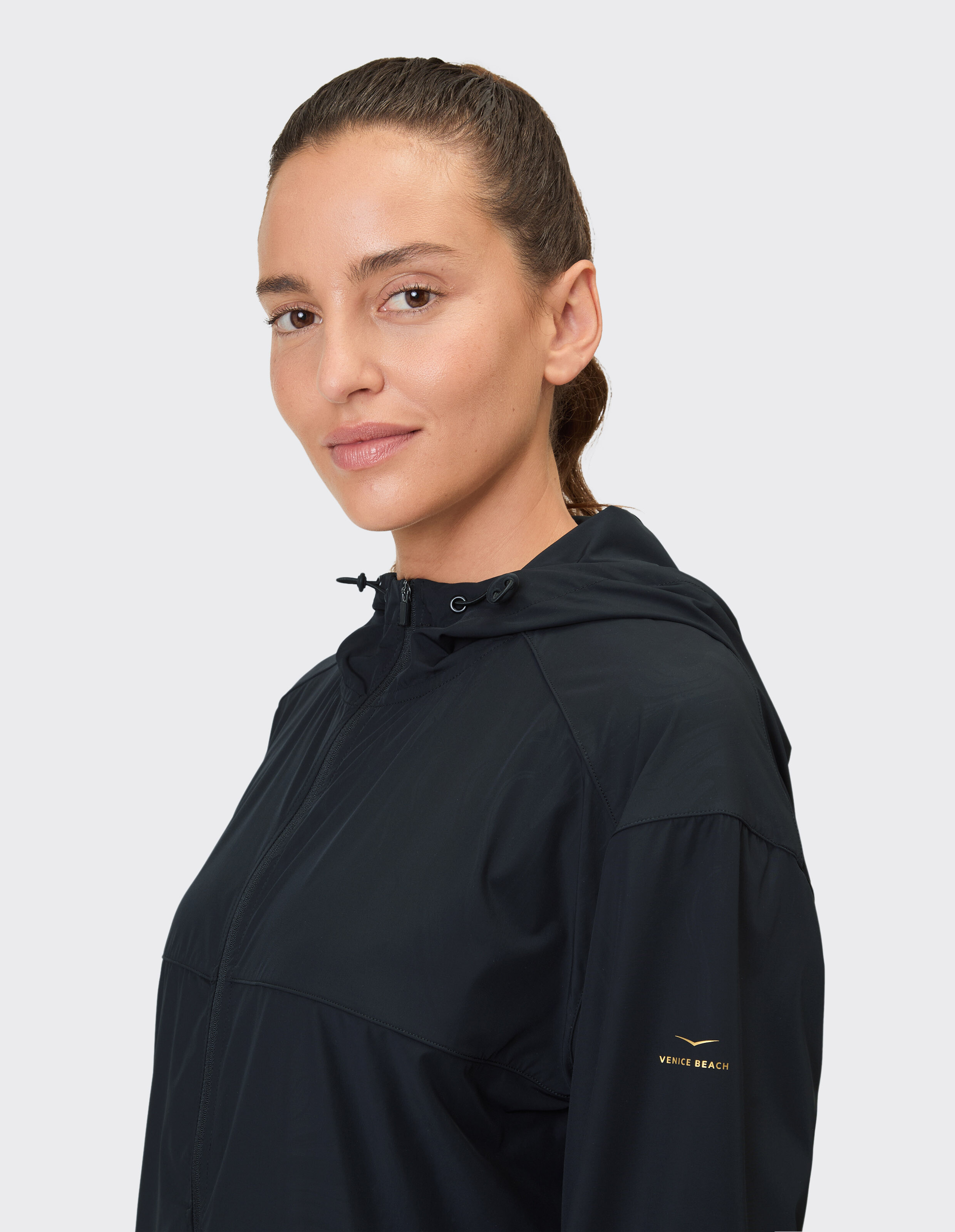 Frau trägt eine schwarze Freizeitjacke mit Kapuze von Venice Beach für Aktivkleidung.