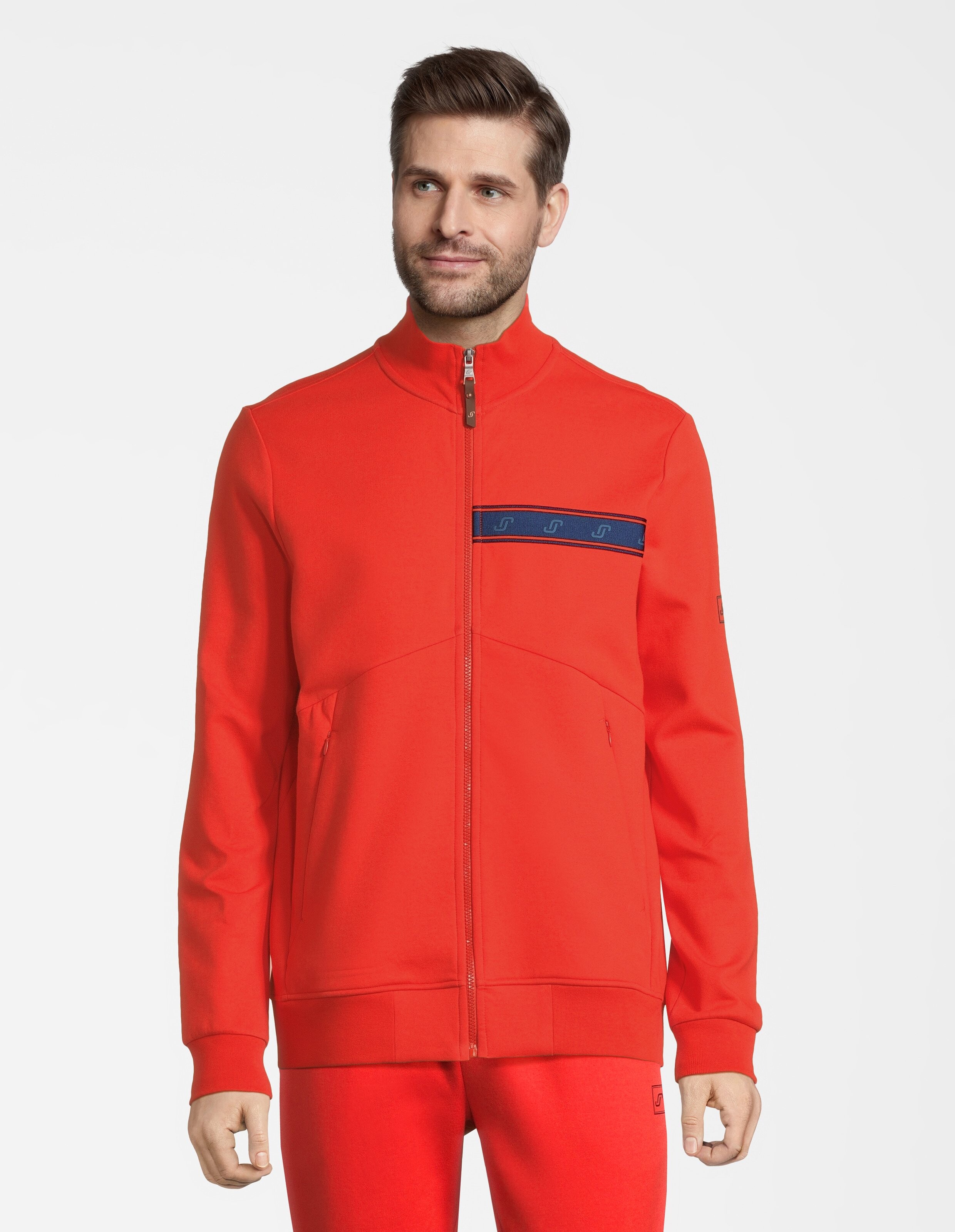 Mann trägt eine rote ELBSAND-Trainingsjacke mit Reißverschluss und Logostreifen für lässige Lounge-Kleidung.