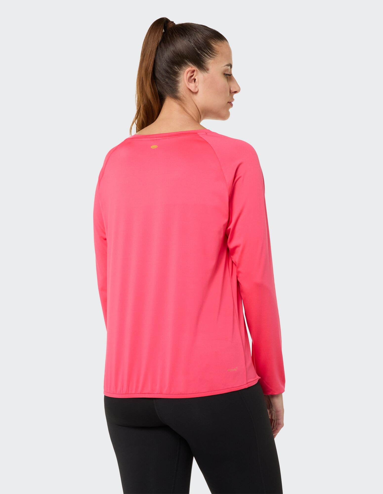Rückansicht einer Frau in einem leuchtend rosa Langarmshirt, gepaart mit schwarzen Leggings.